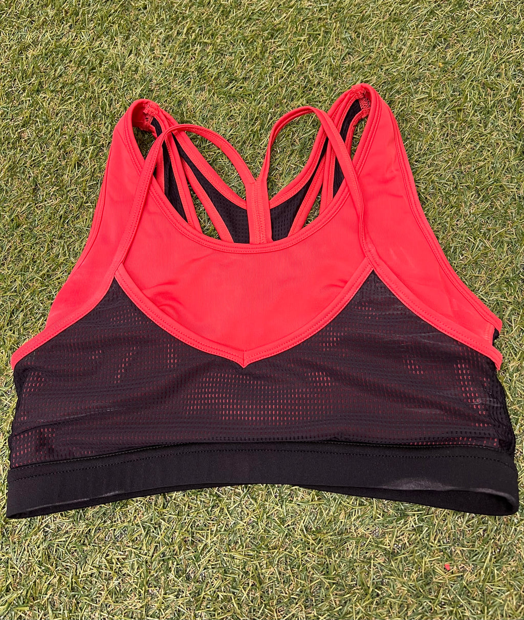 Front view of Crane sports bra top in vibrant orange and black with mesh panels