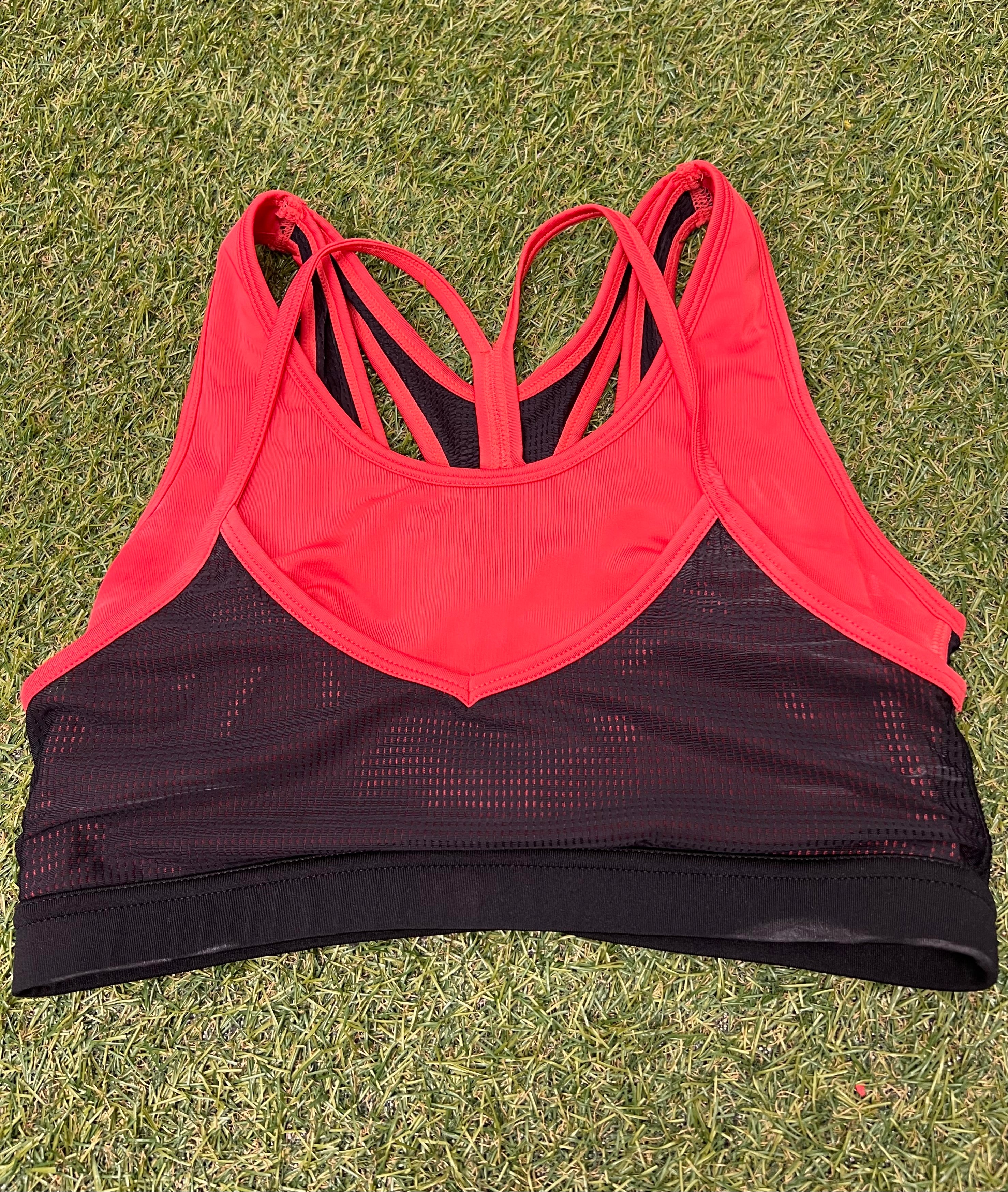 Front view of Crane sports bra top in vibrant orange and black with mesh panels