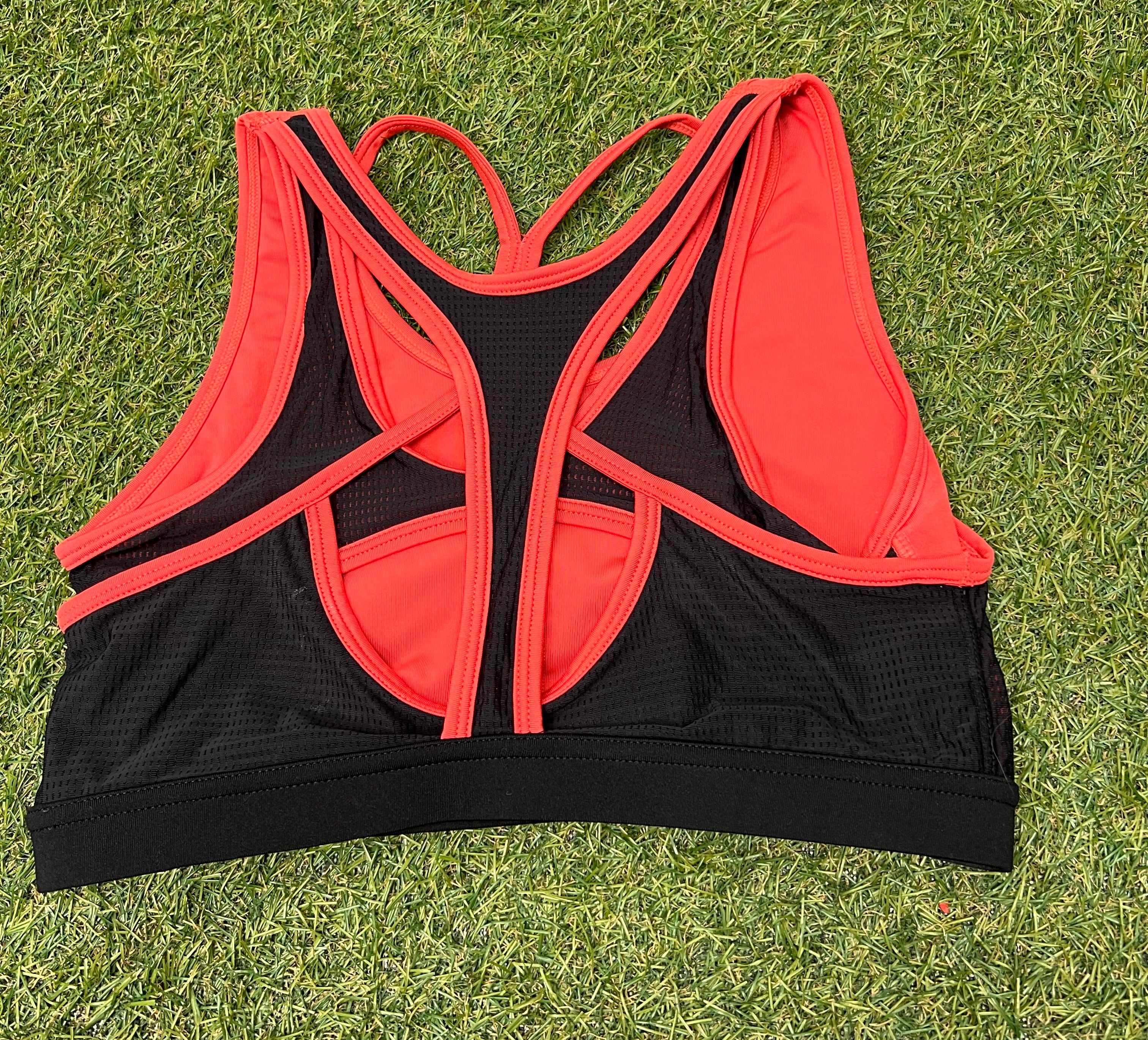 Back view of Crane sports bra showcasing strappy racerback design in orange and black mesh