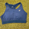 Front view of Asics blue sports bra laid flat on grass