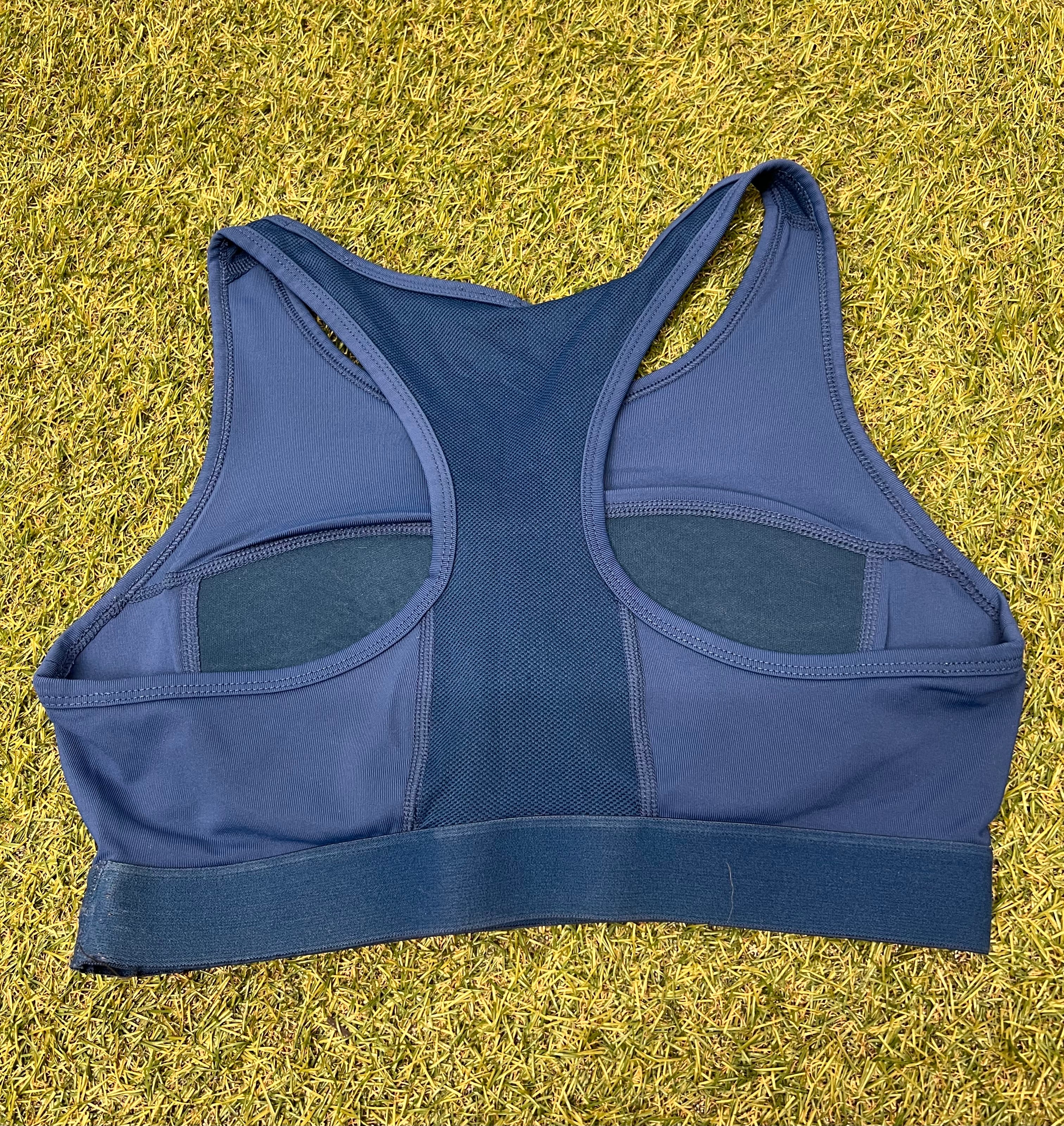 Back view of Asics blue sports bra featuring racerback and mesh panel