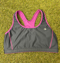 Front view of Champion sports bra top in grey with violet trim on grass