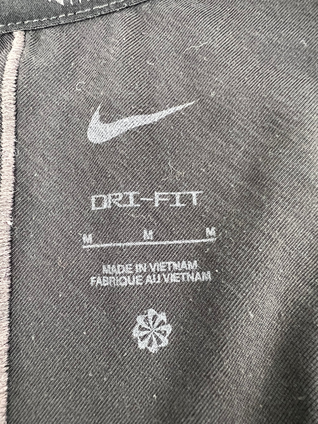 Close-up of the inside label on Nike black Dri-FIT training vest indicating size medium and made in Vietnam