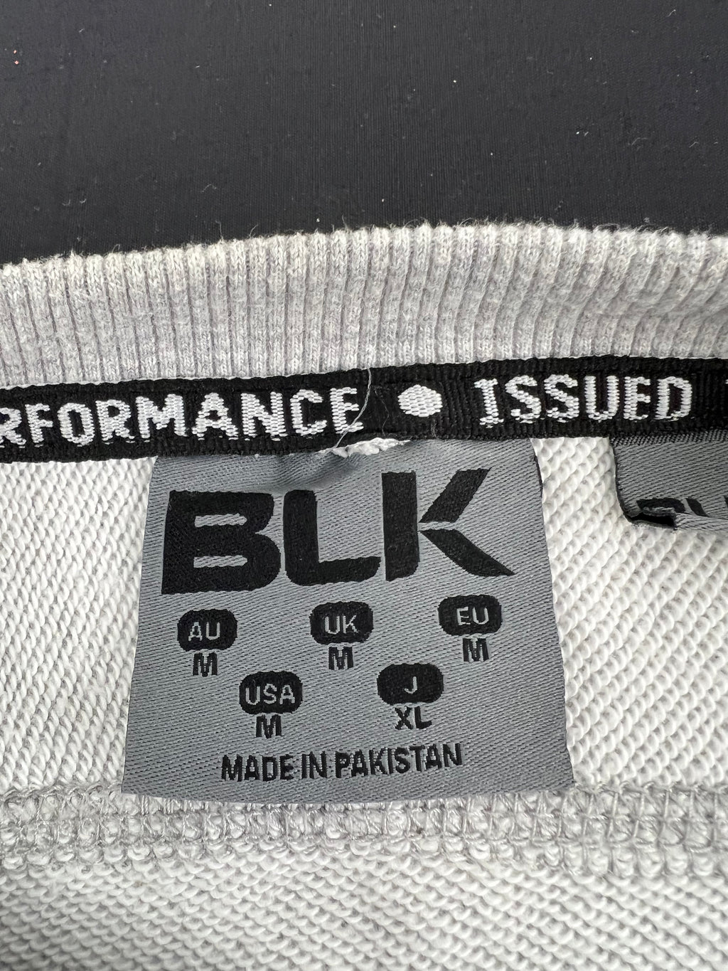 Close-up of BLK sweatshirt label showing size medium and made in Pakistan