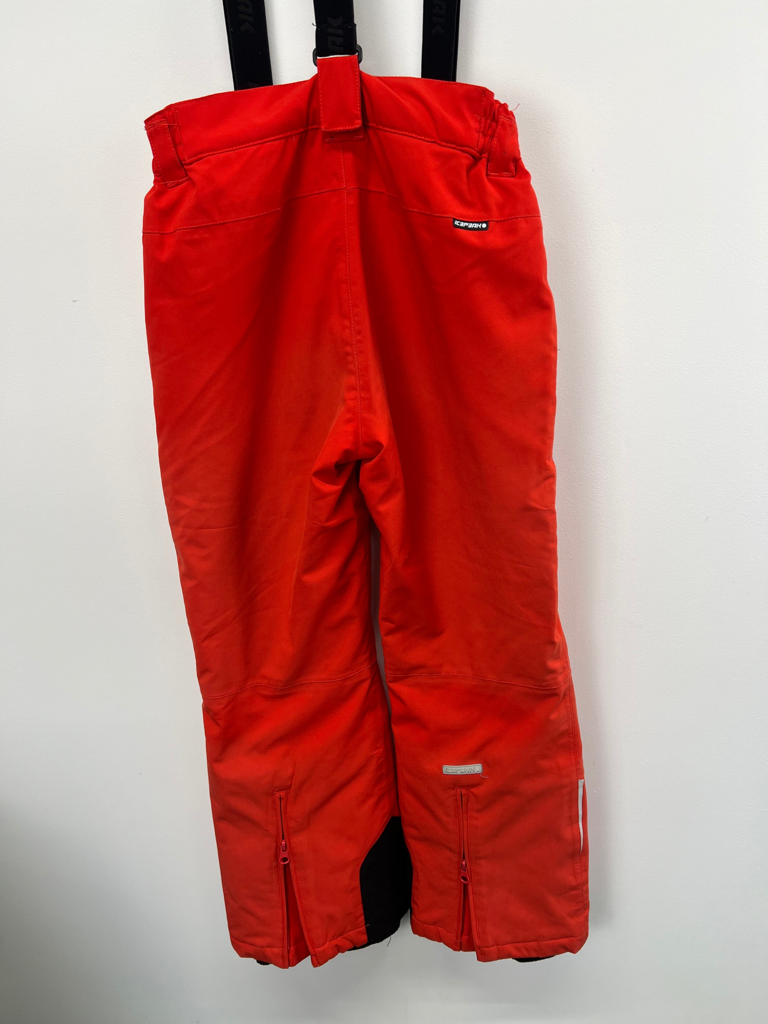 Close-up of lower leg section of red skiing trousers with zippered vents and reinforced black cuffs
