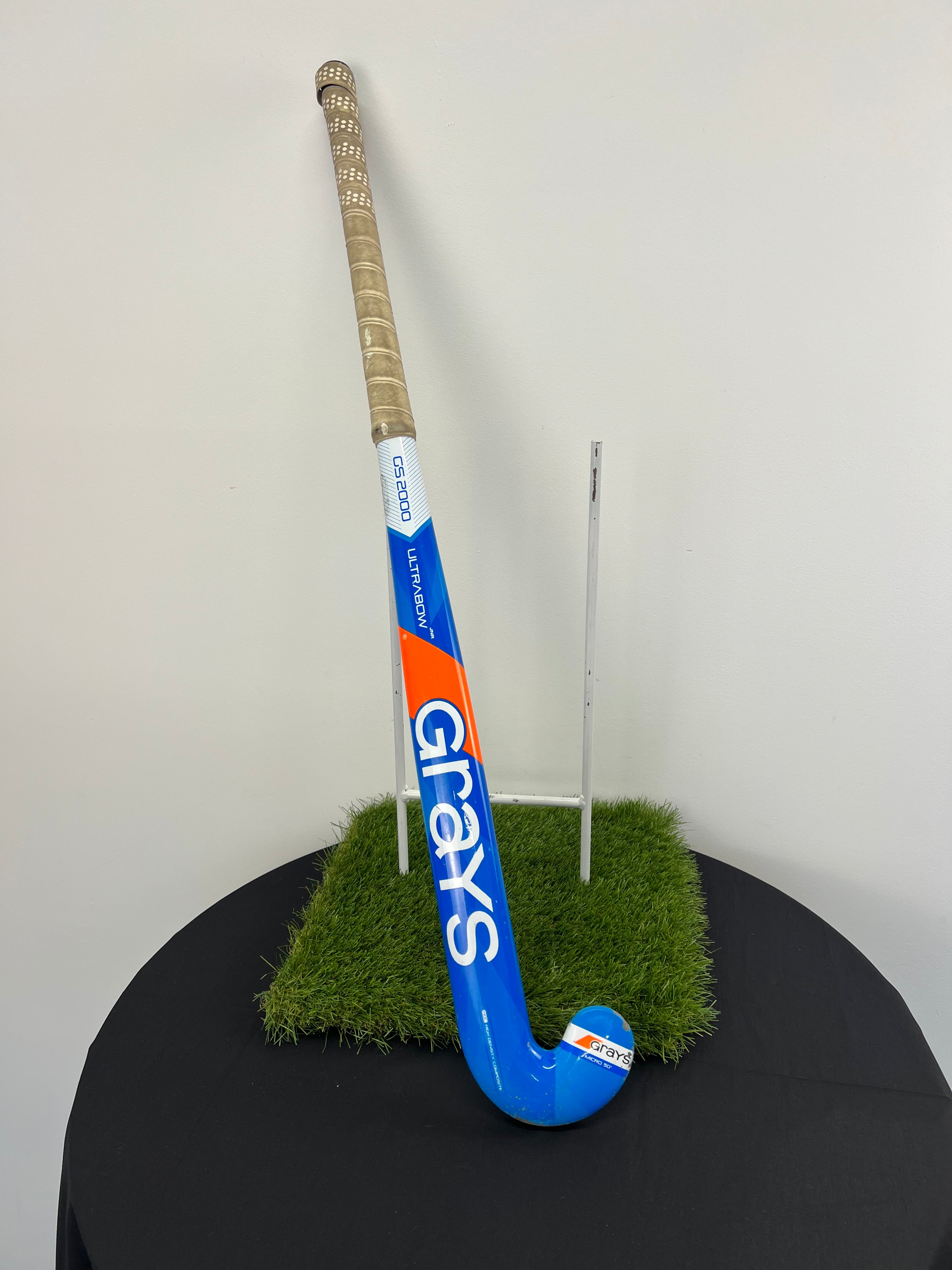 Full view of Grays Ultrabow Jnr Micro 50” hockey stick standing against white wall