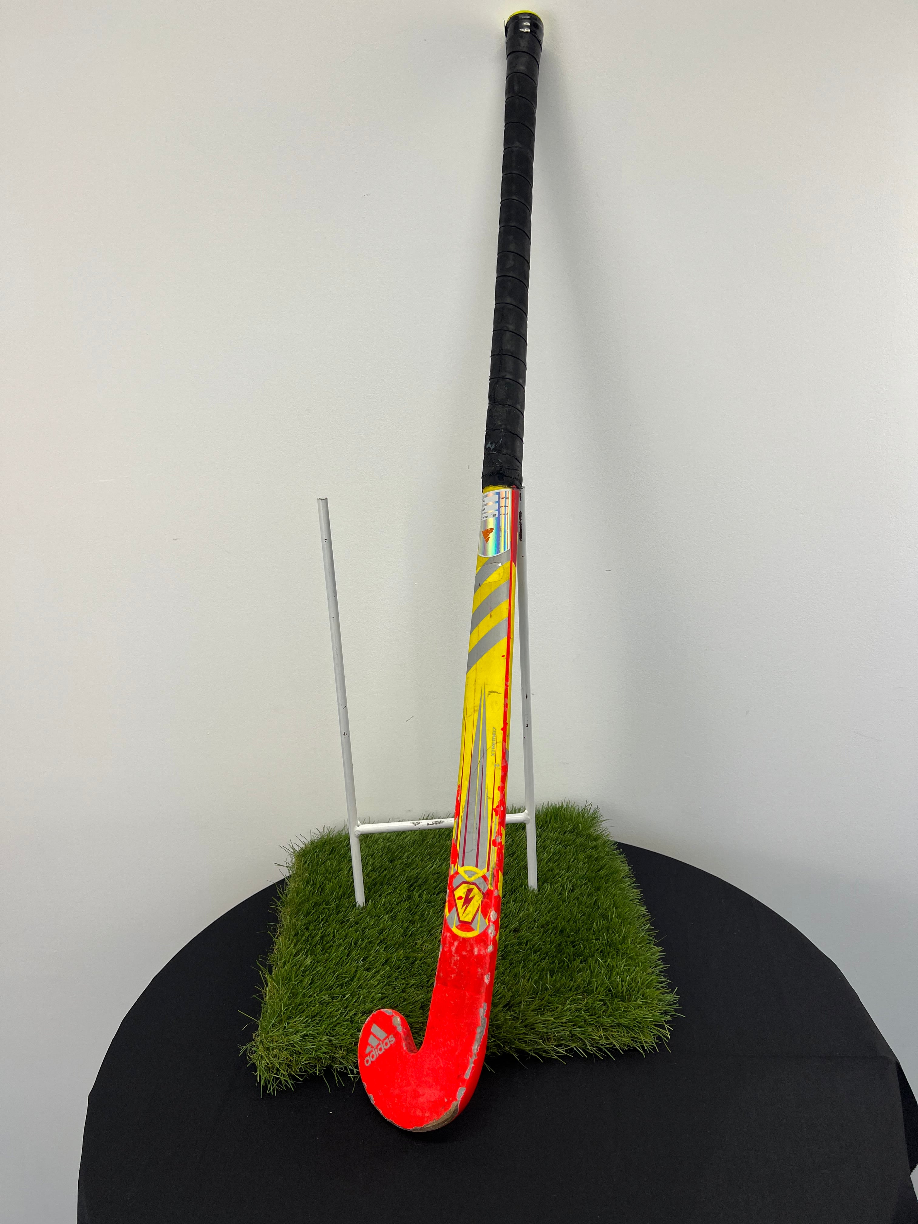 Front view of used adidas 35 inch junior hockey stick showing silver, yellow and red graphics with some wear