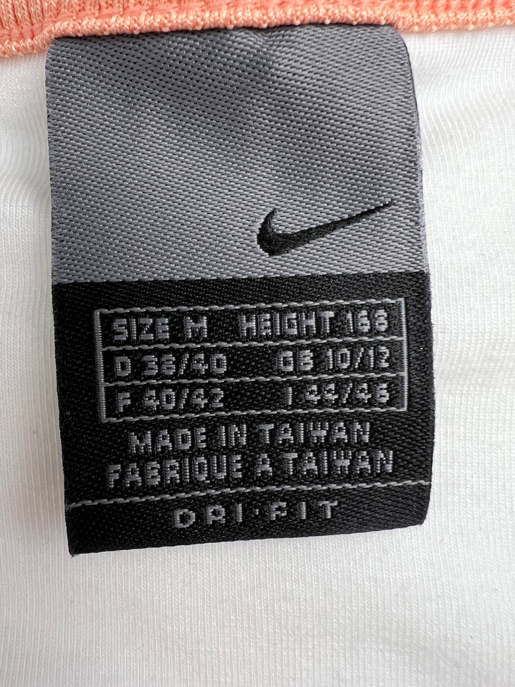 Close-up of Nike label on tennis dress showing size M, Dri-FIT technology and made in Taiwan tag