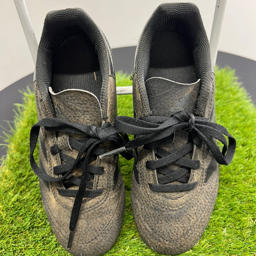 Top view of adidas black kids football boots with laces on artificial grass