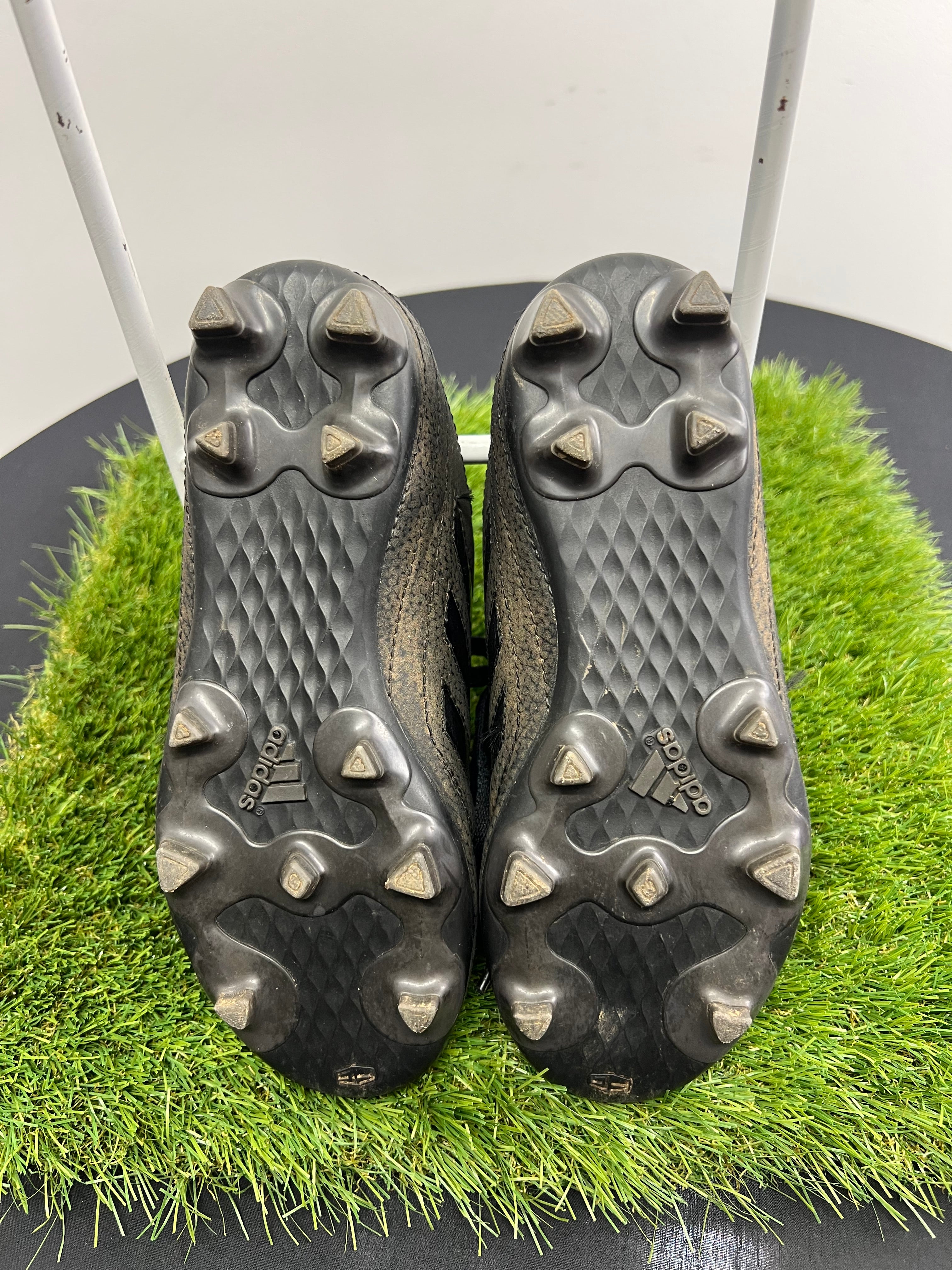 underside view showing black soleplate with moulded studs on kids adidas football boots
