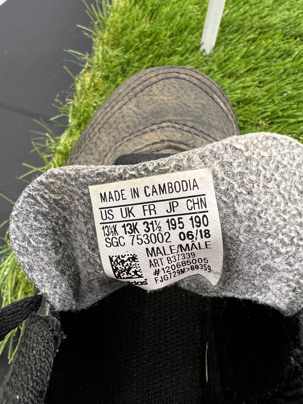 close-up of size label inside kids adidas black football boots, made in Cambodia, size UK 13K