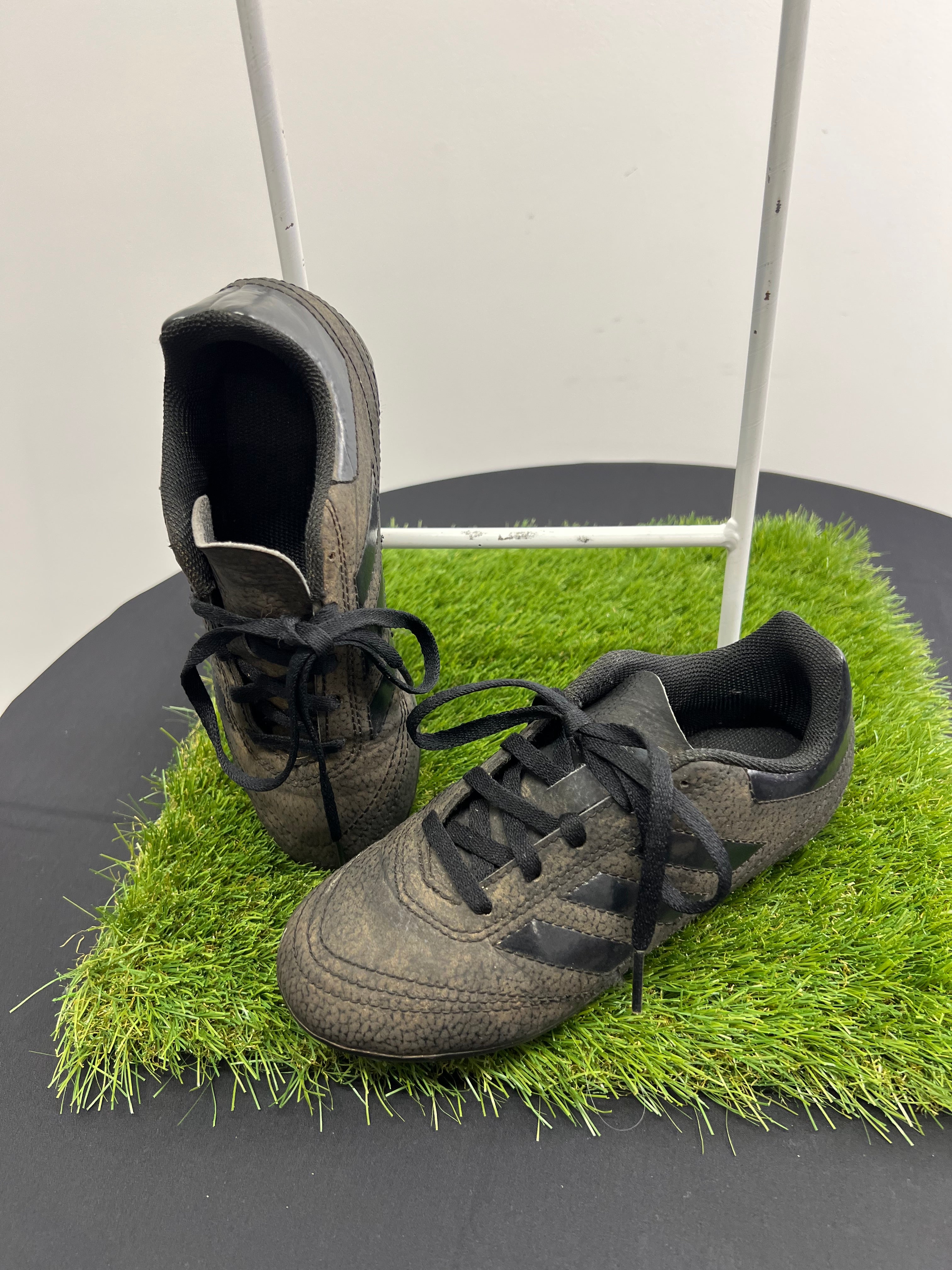 angled top and side view of black adidas kids football boots on artificial grass