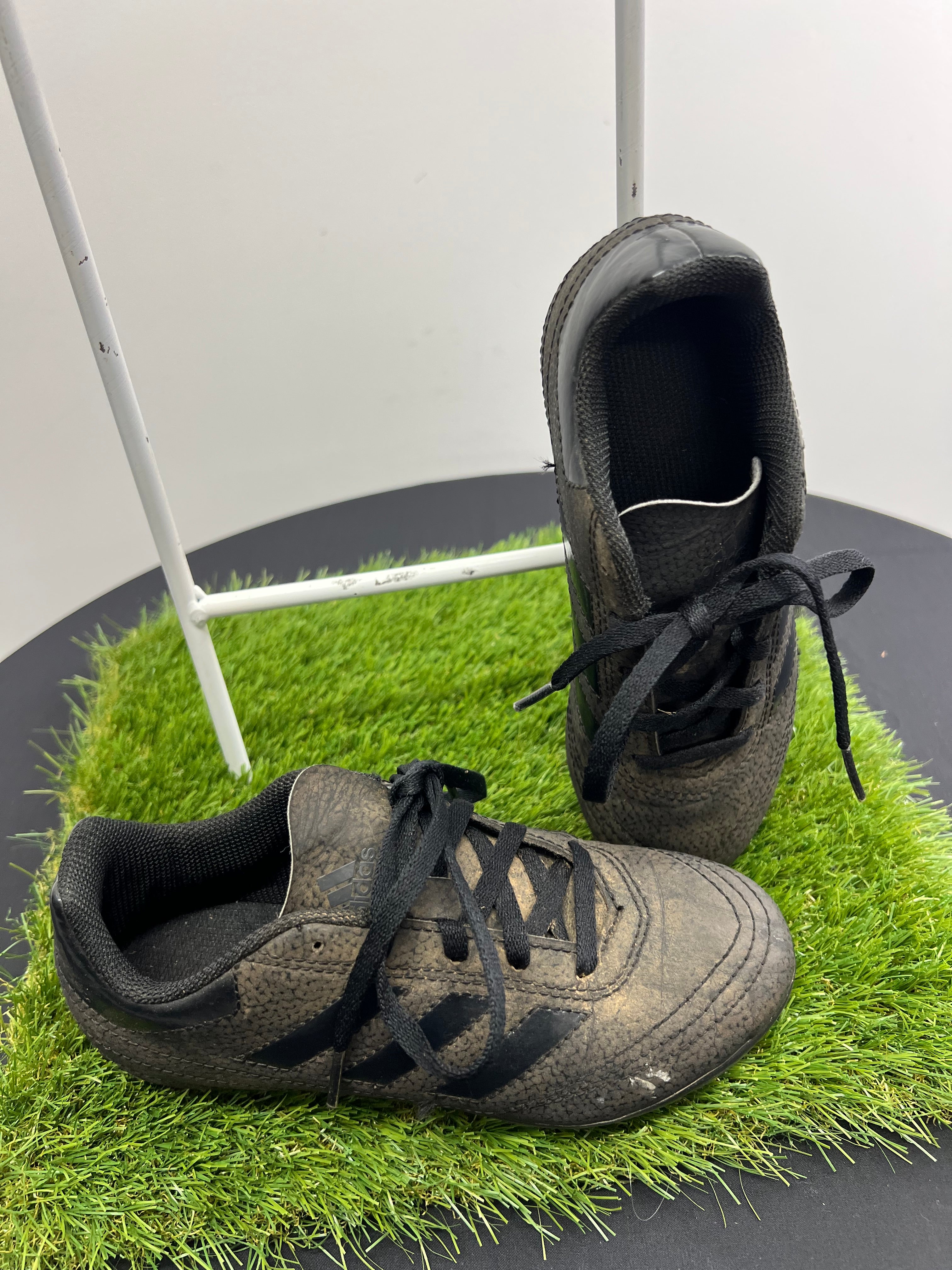 angled side view of kids adidas black football boots showing laces, stripes and stitched details