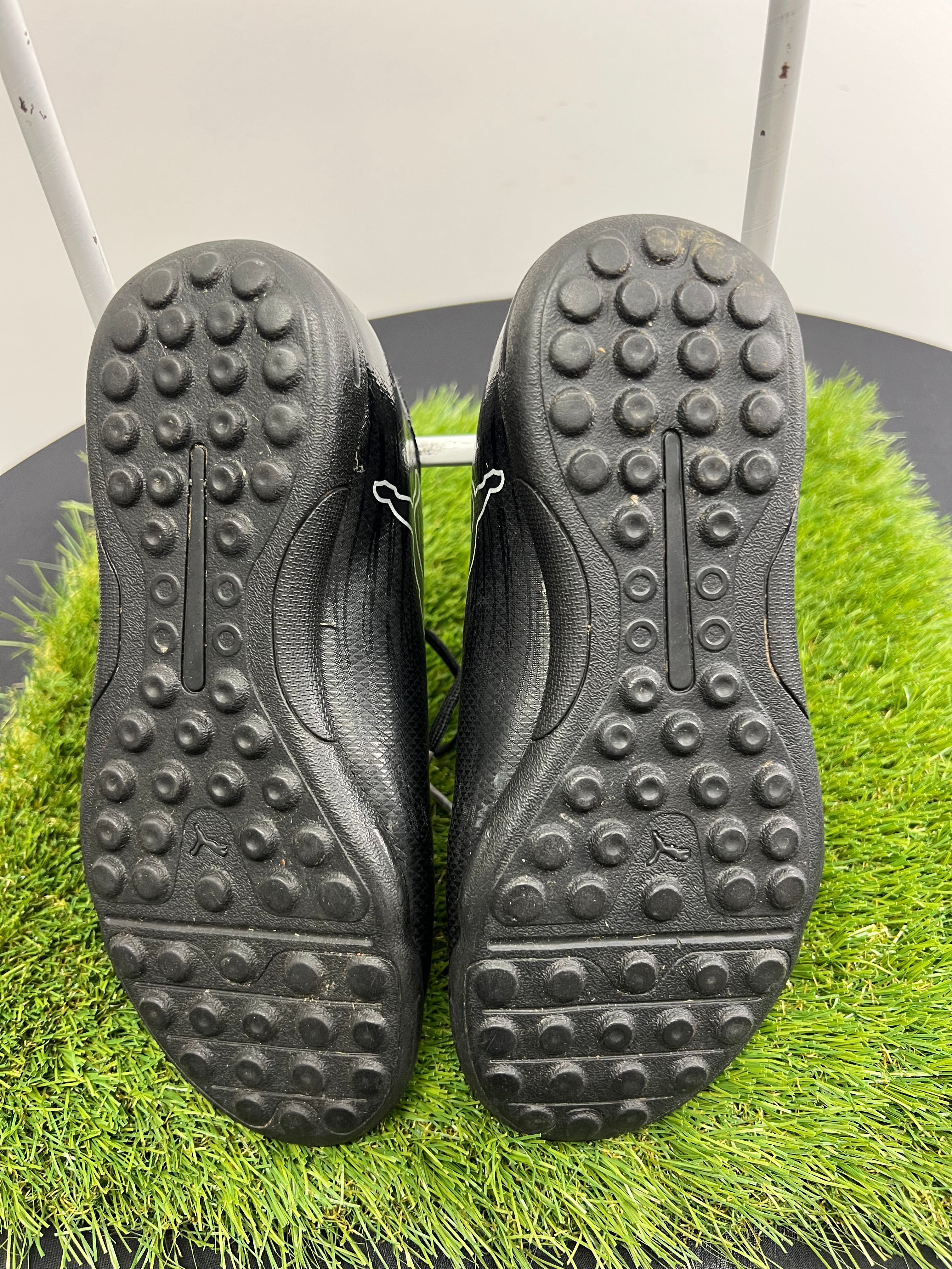 Underside view showing rubber studded soles of black Puma kids football boots size 13