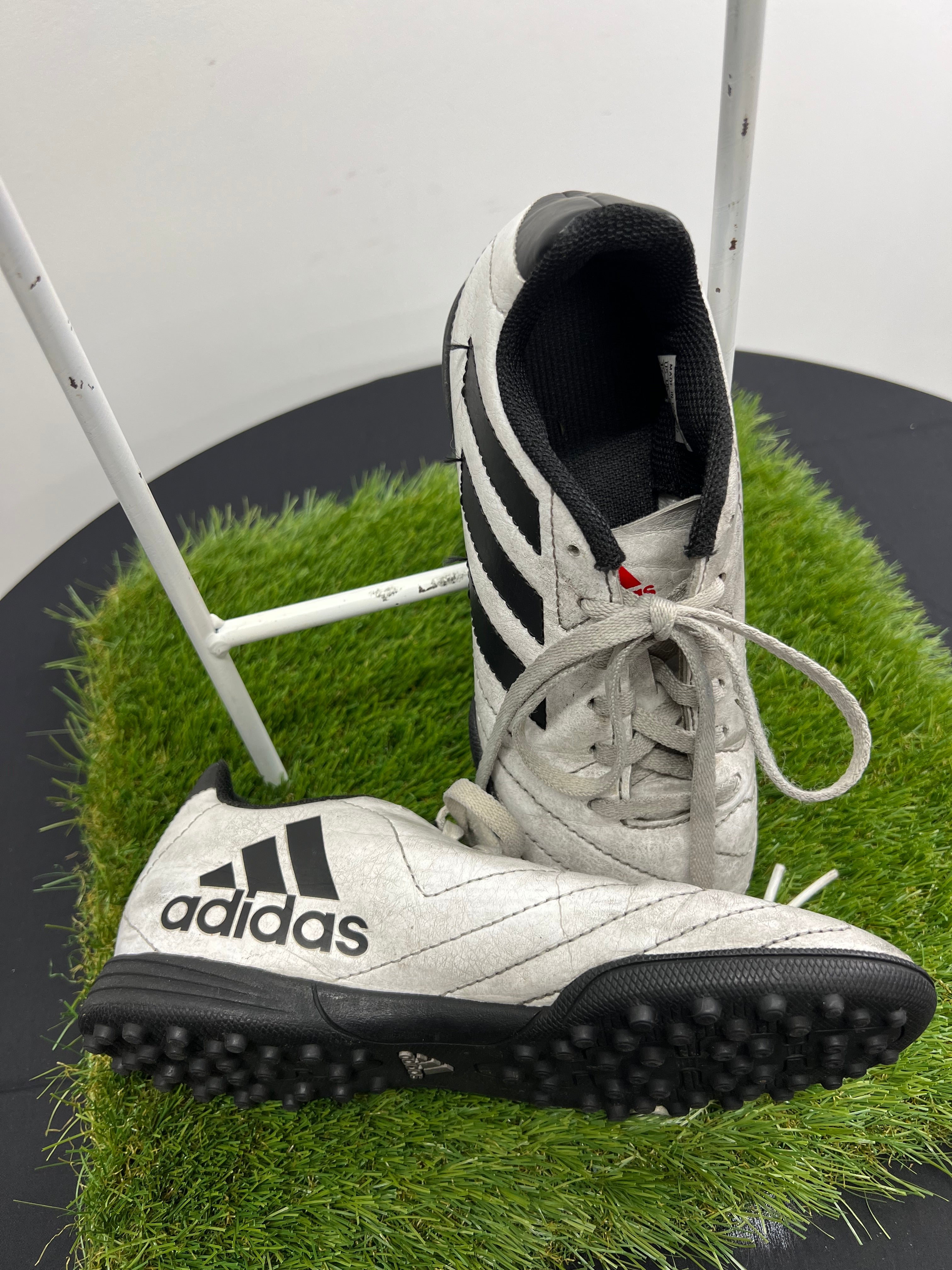 Side and angled view of single kids adidas Astro turf boot highlighting black stripes and sole