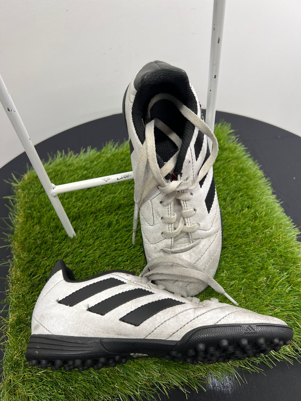 Top and side perspective of the pair of white and black adidas Astro turf boots for kids