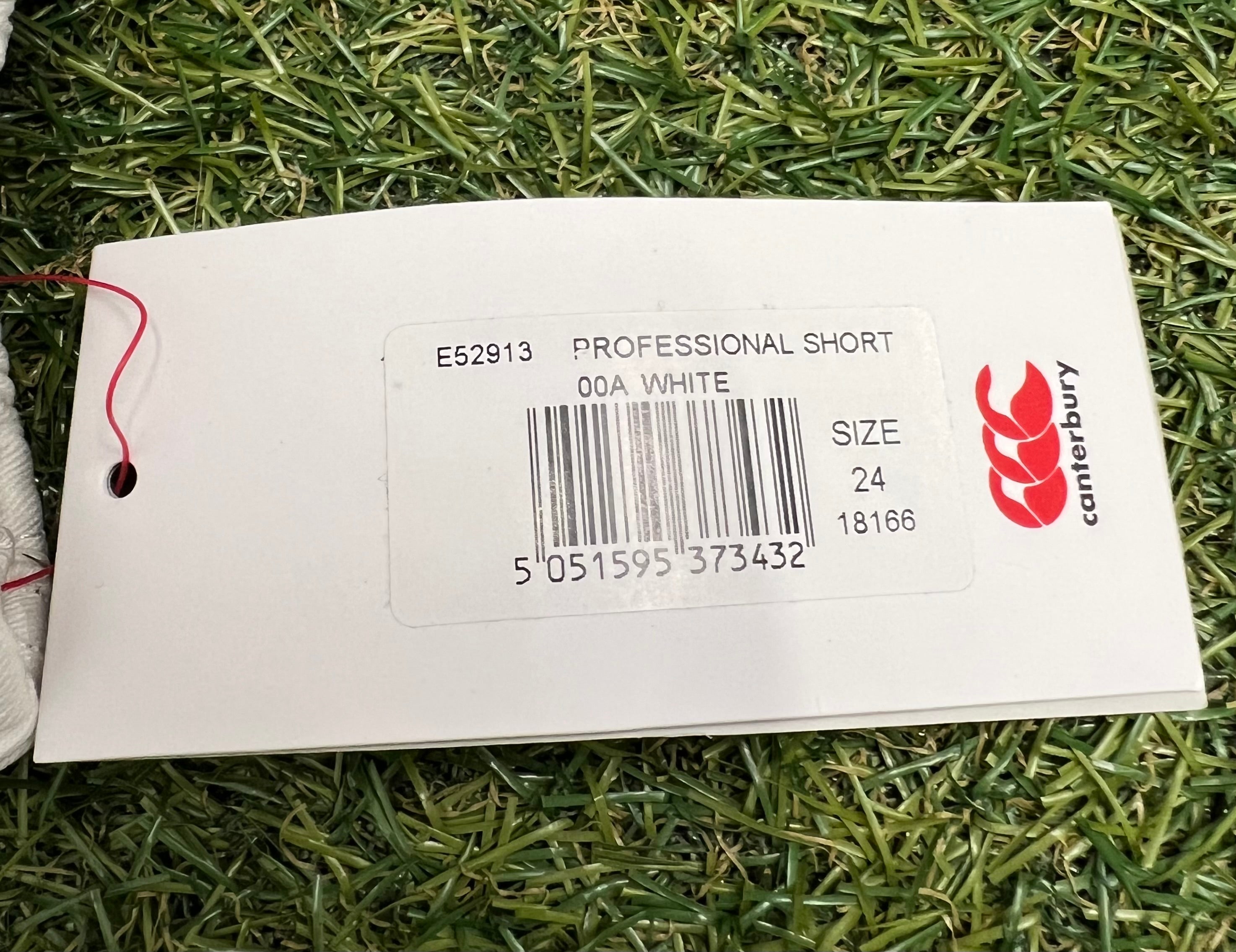 Close-up of Canterbury professional short size tag and barcode on grass