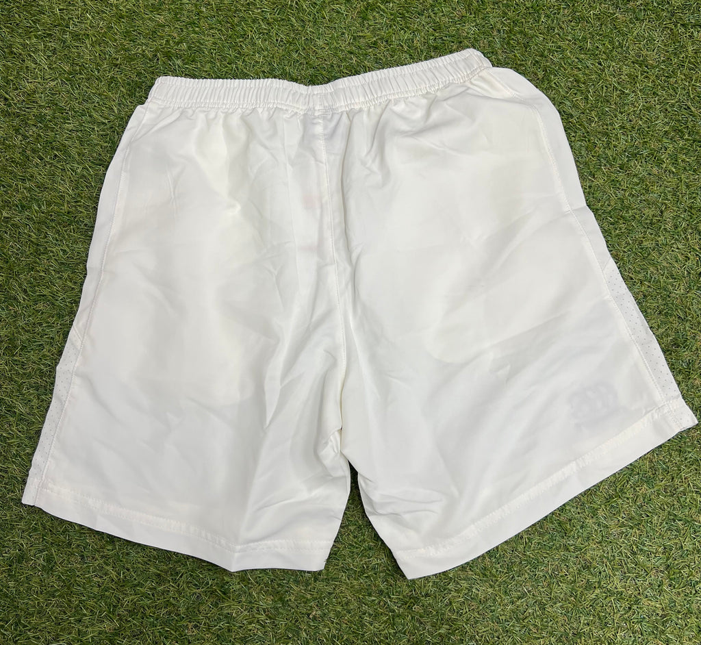 Back view of men’s Canterbury white team sports shorts on grass showing clean design and breathable side panels