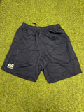 Front view of navy Canterbury men's team shorts laid flat on grass surface showing elastic waistband and logo