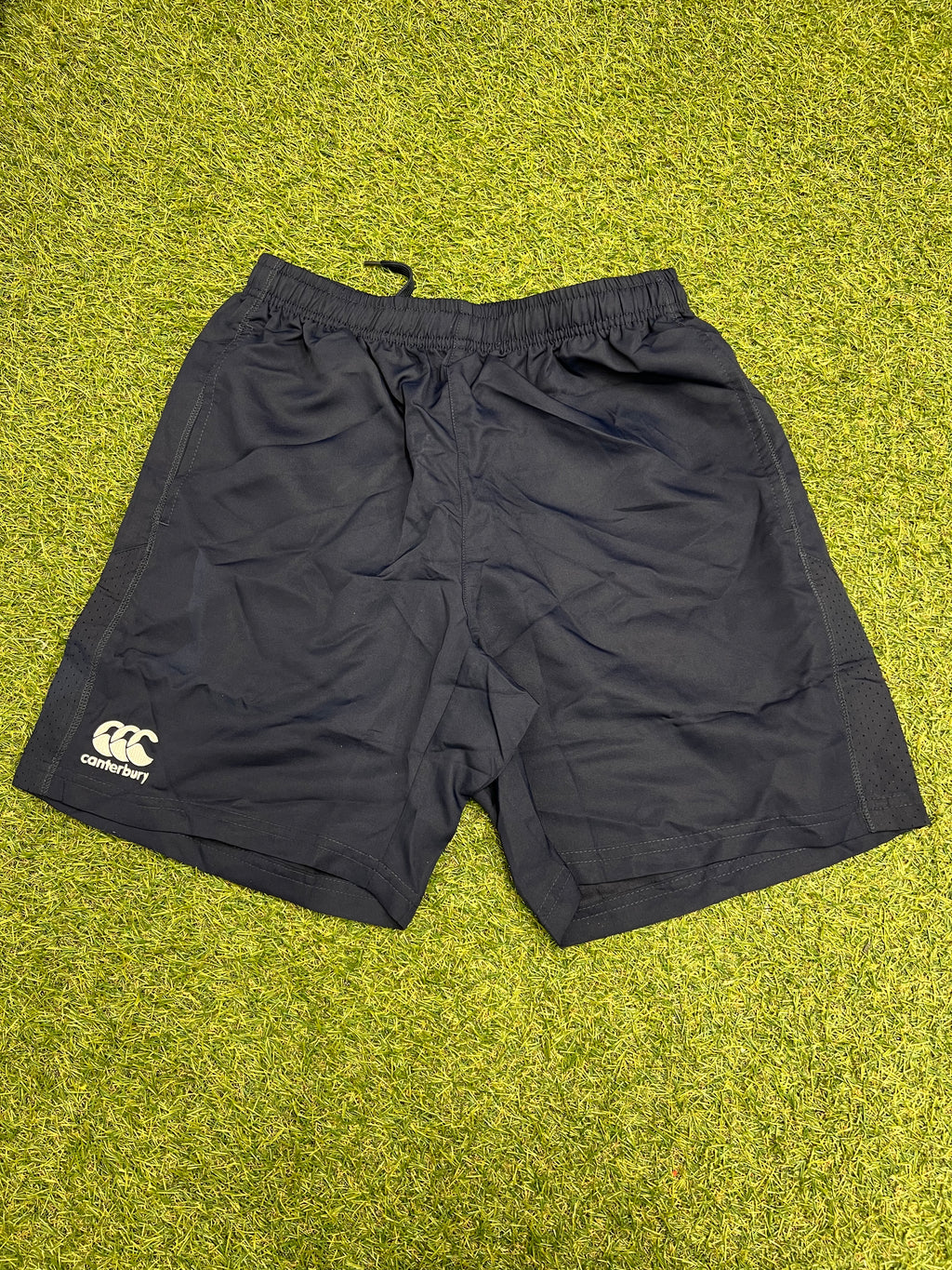Front view of men’s Canterbury navy team shorts laid flat on grass