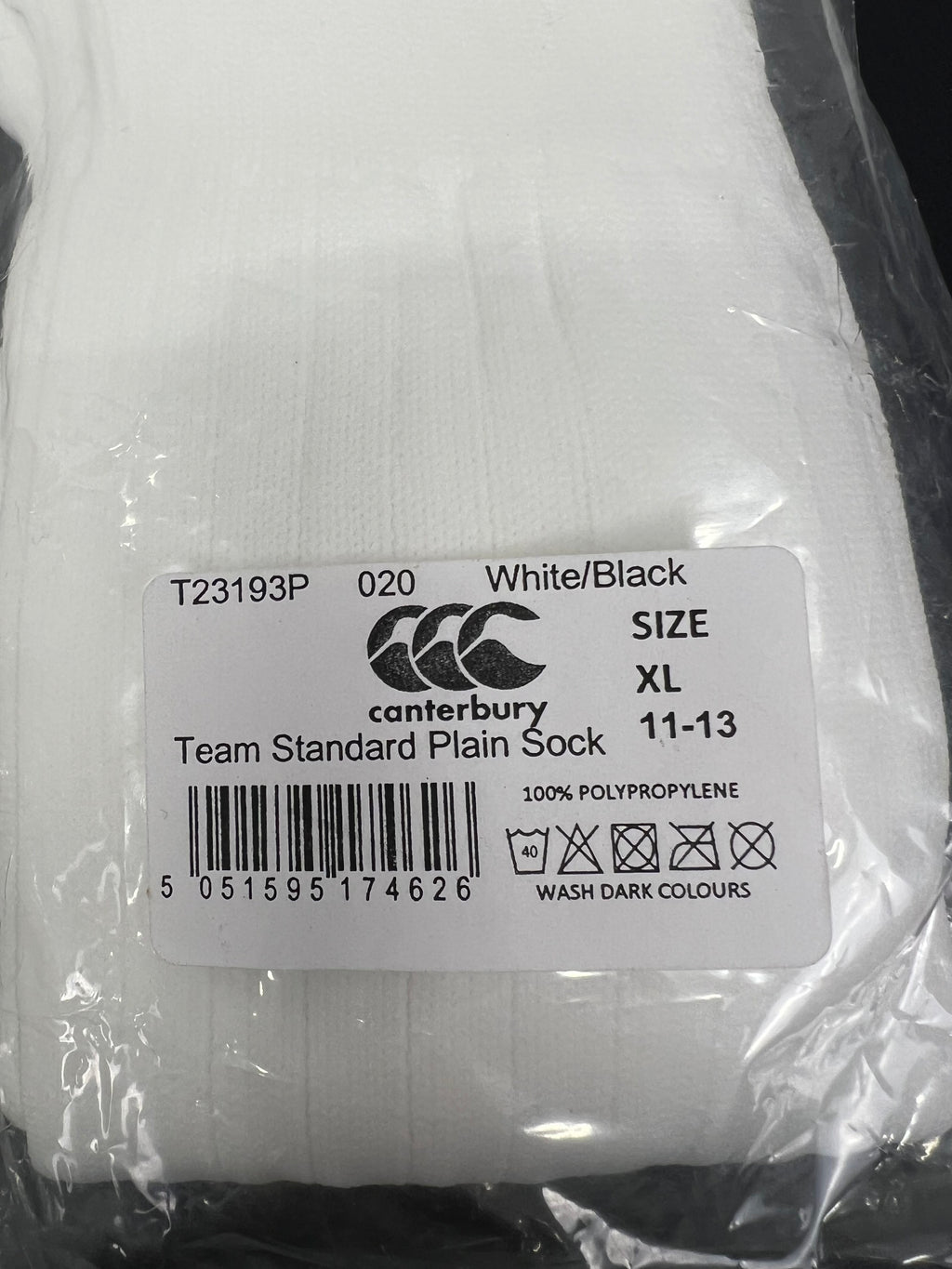 Close-up of Canterbury label on a pair of white men's team socks, size XL 11-13, 100% polypropylene