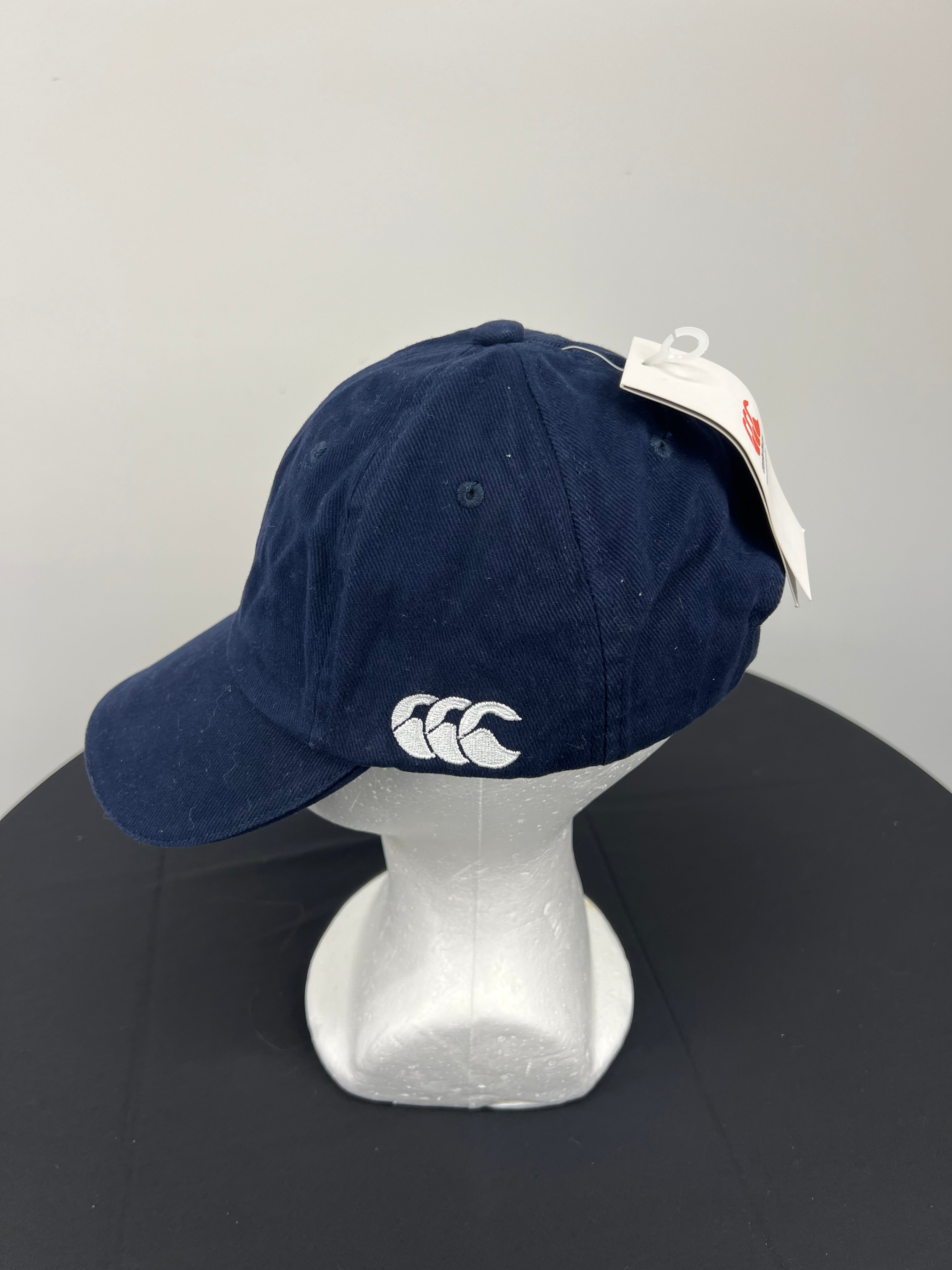 Side view of navy Canterbury cap showing white embroidered logo