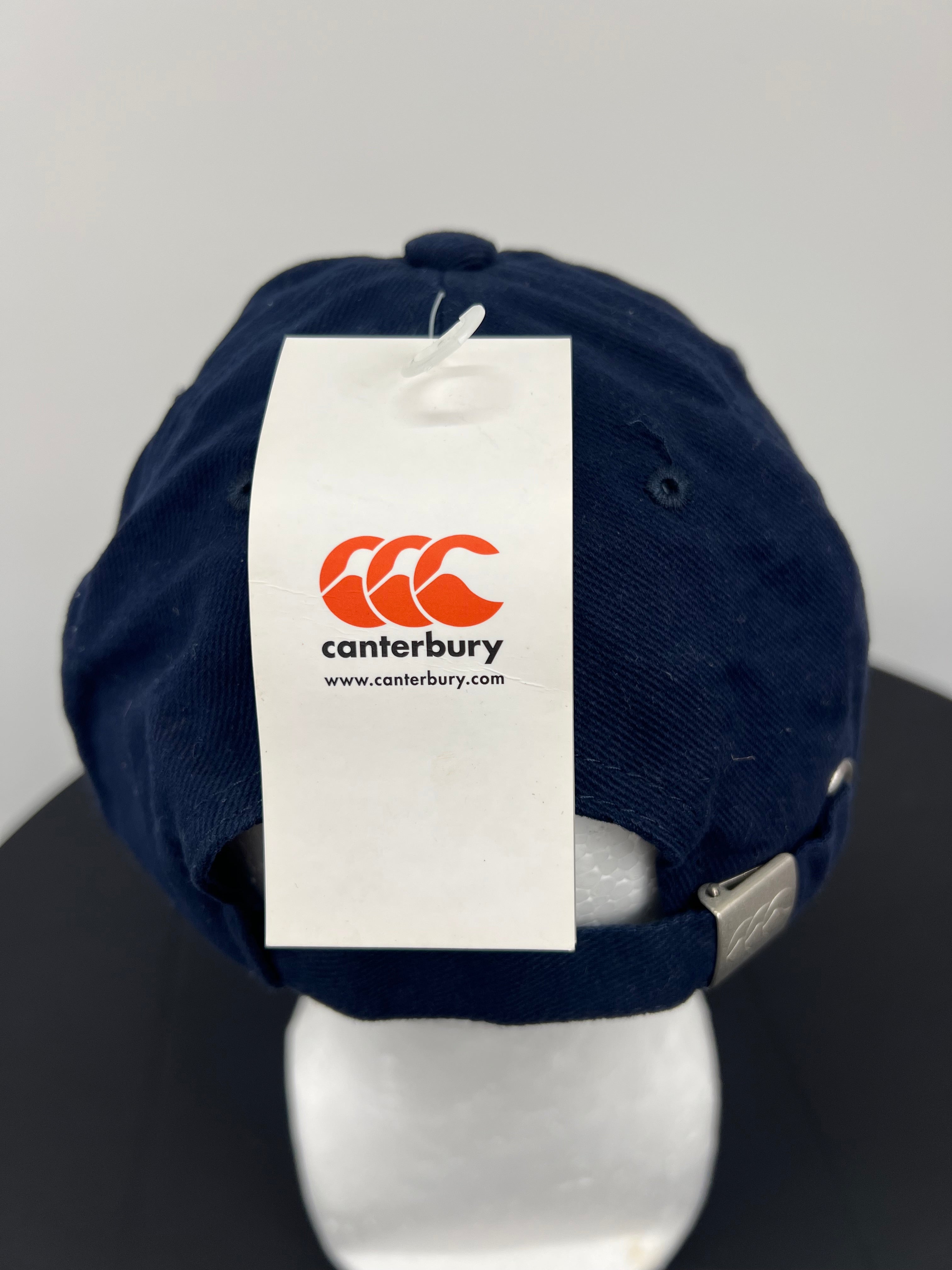 Close-up of Canterbury brand tag on back strap of navy cap
