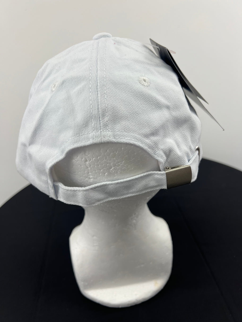 Rear view of white Canterbury cap featuring adjustable strap with silver buckle