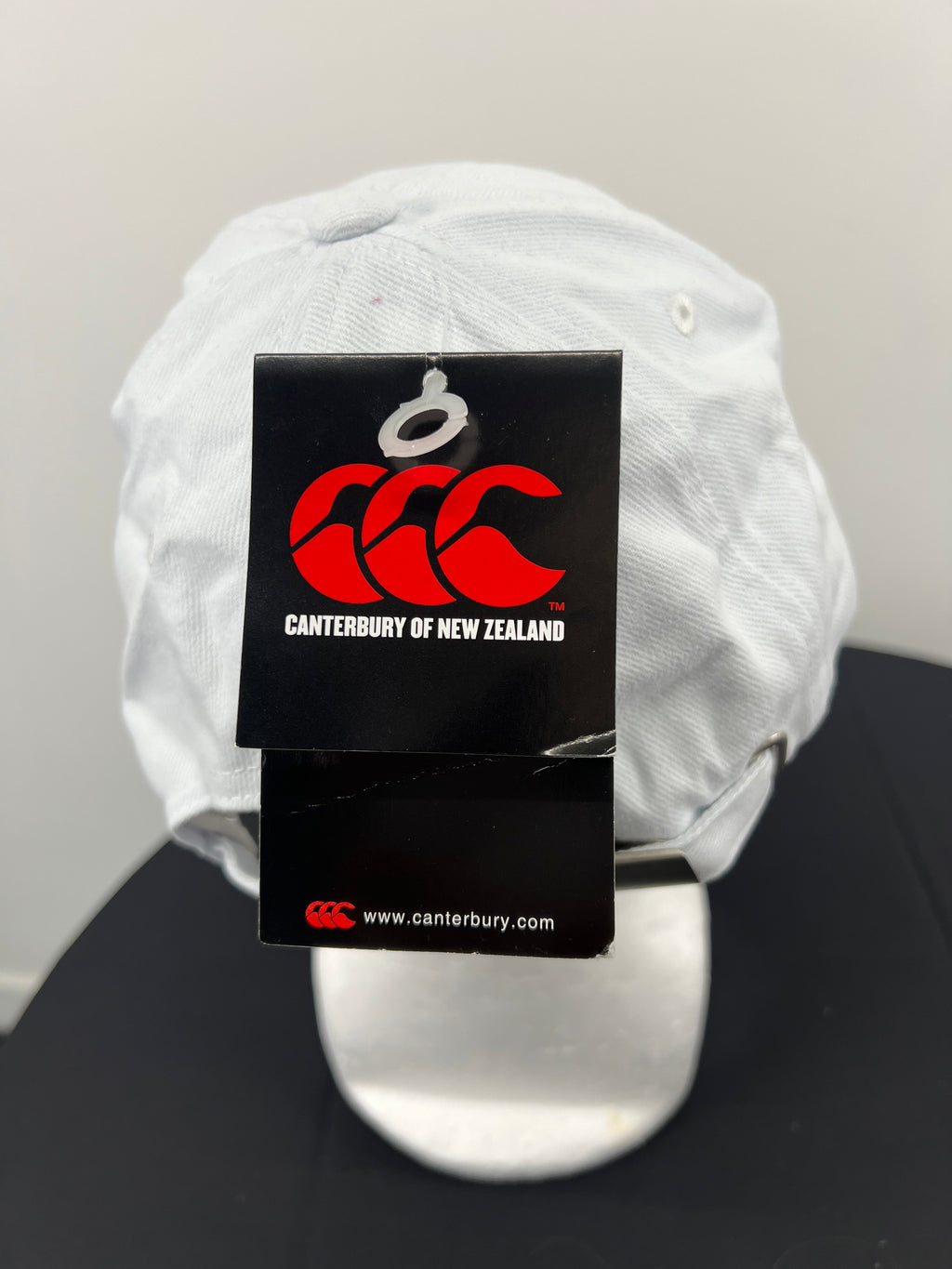 Close-up of black Canterbury brand tag hanging from the adjustable white cap