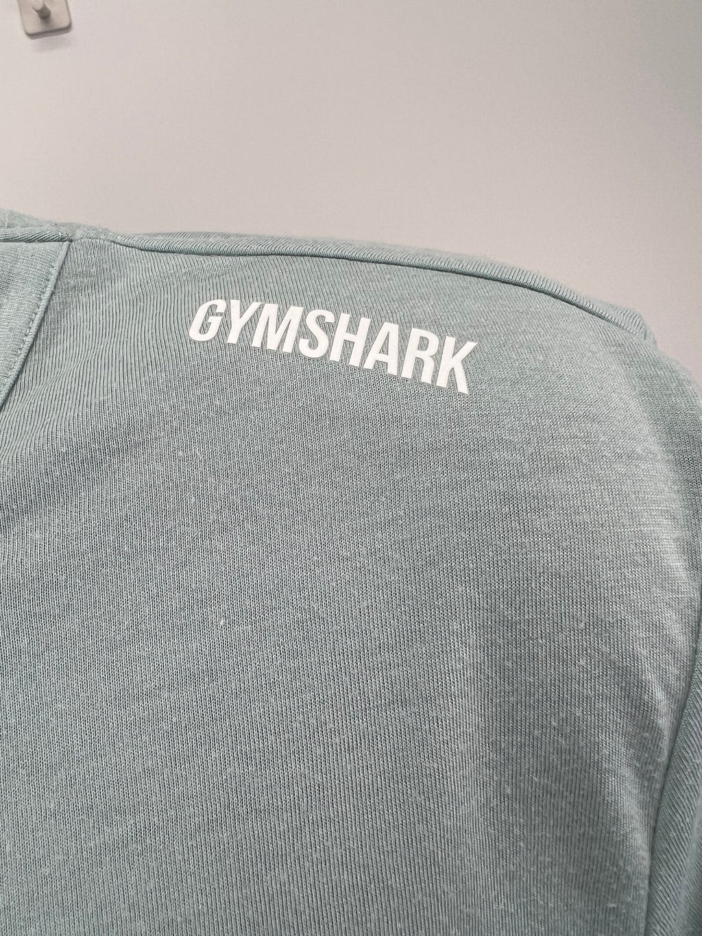 Close-up of Gymshark logo on shoulder of light green t-shirt