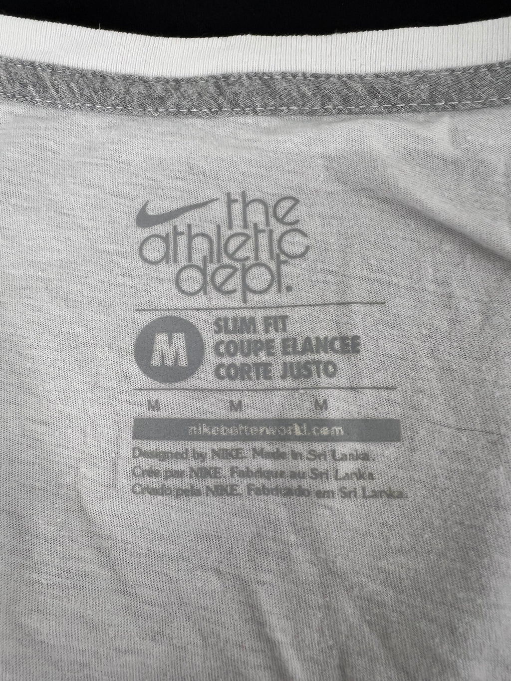 Close-up of inner label on Nike slim fit white t-shirt showing size M and brand details