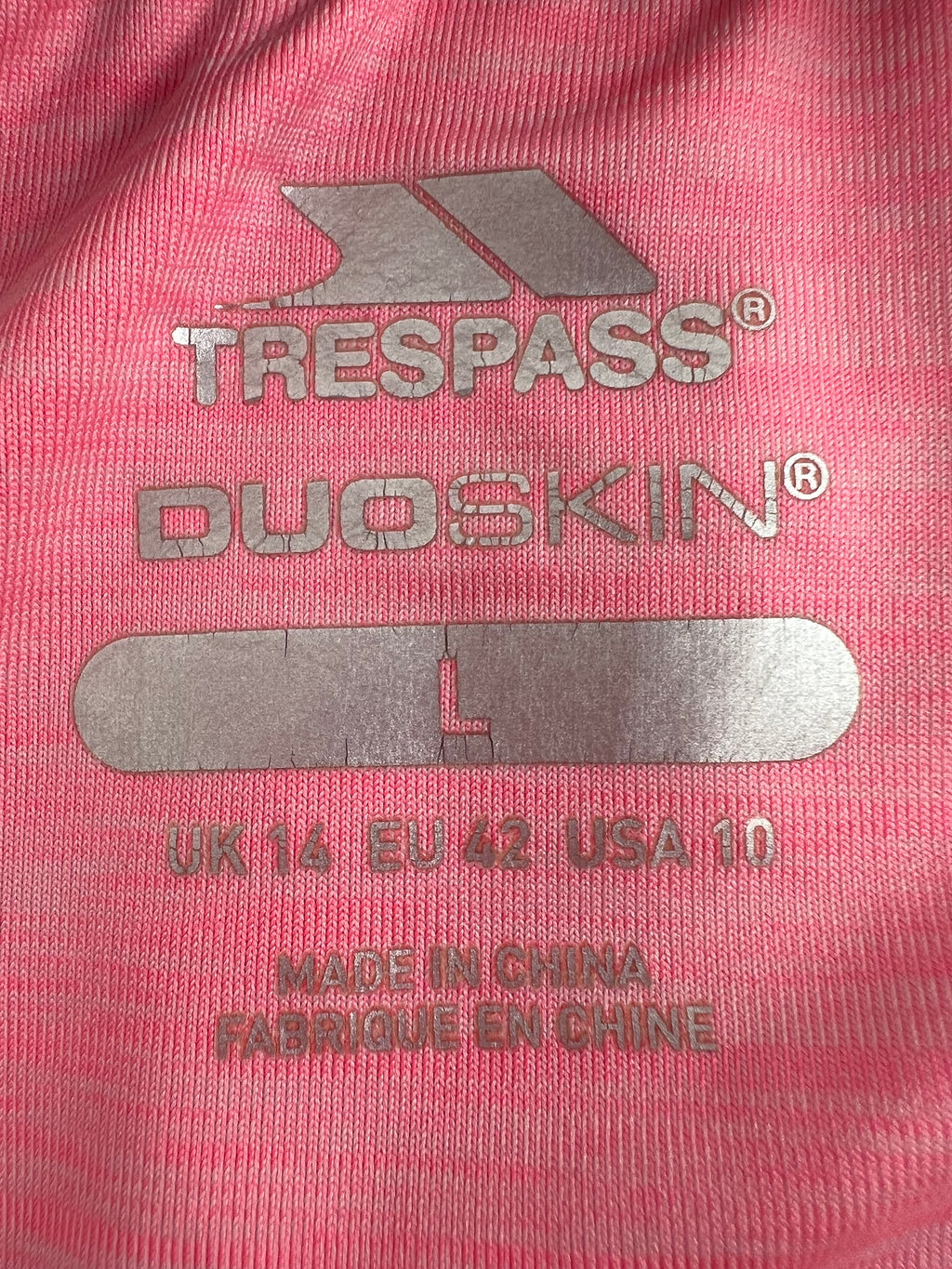 Close-up of Trespass Duoskin logo and size label printed on pink t-shirt