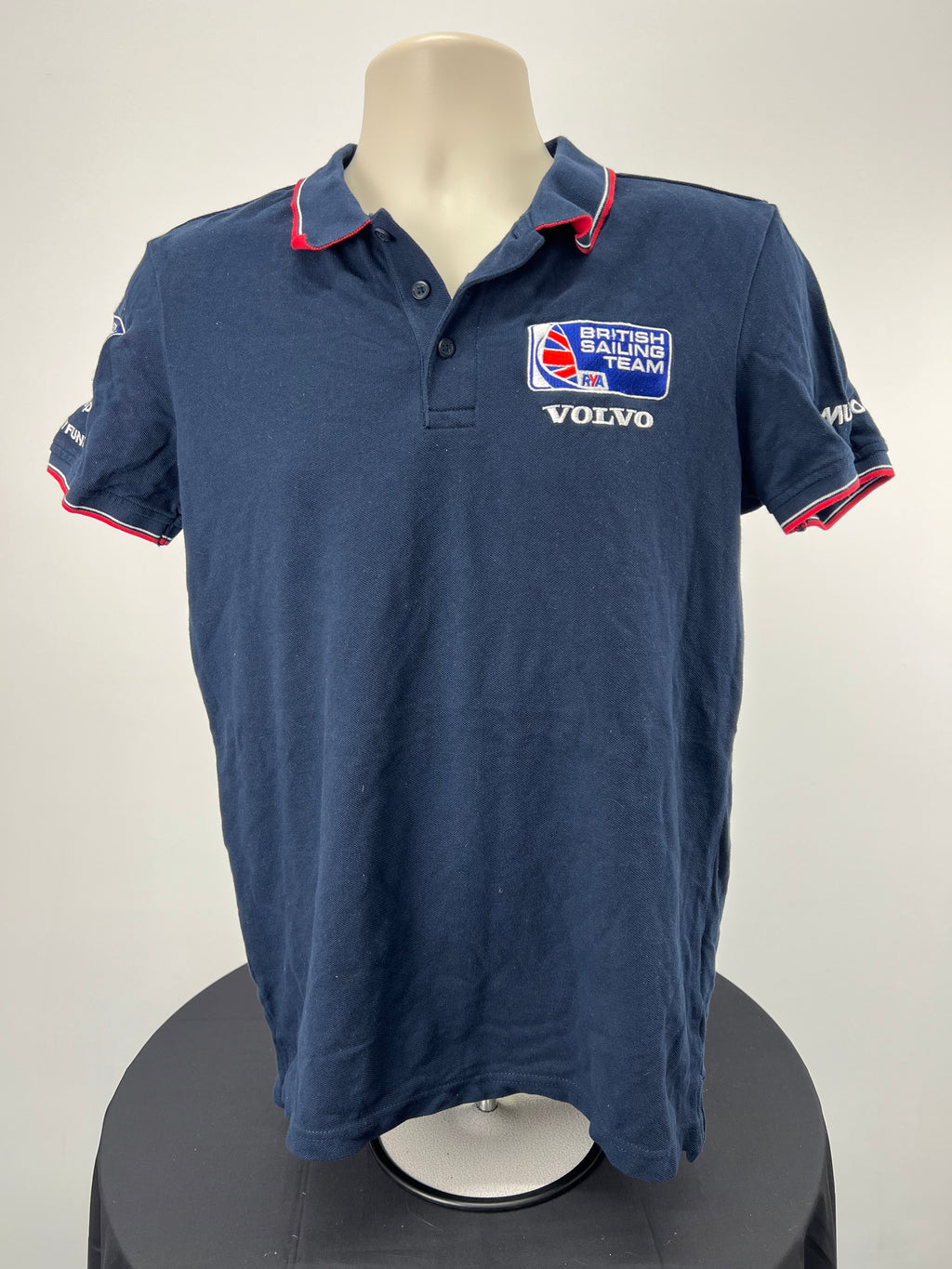 Front view of navy British Sailing Team polo shirt with Volvo and Musto branding on collar and sleeves