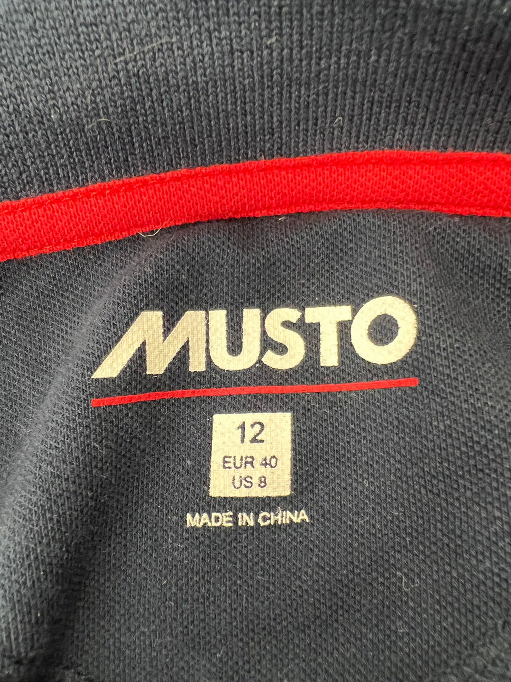 Label inside polo shirt showing Musto brand logo, size 12 UK, EUR 40, US 8, and Made in China text