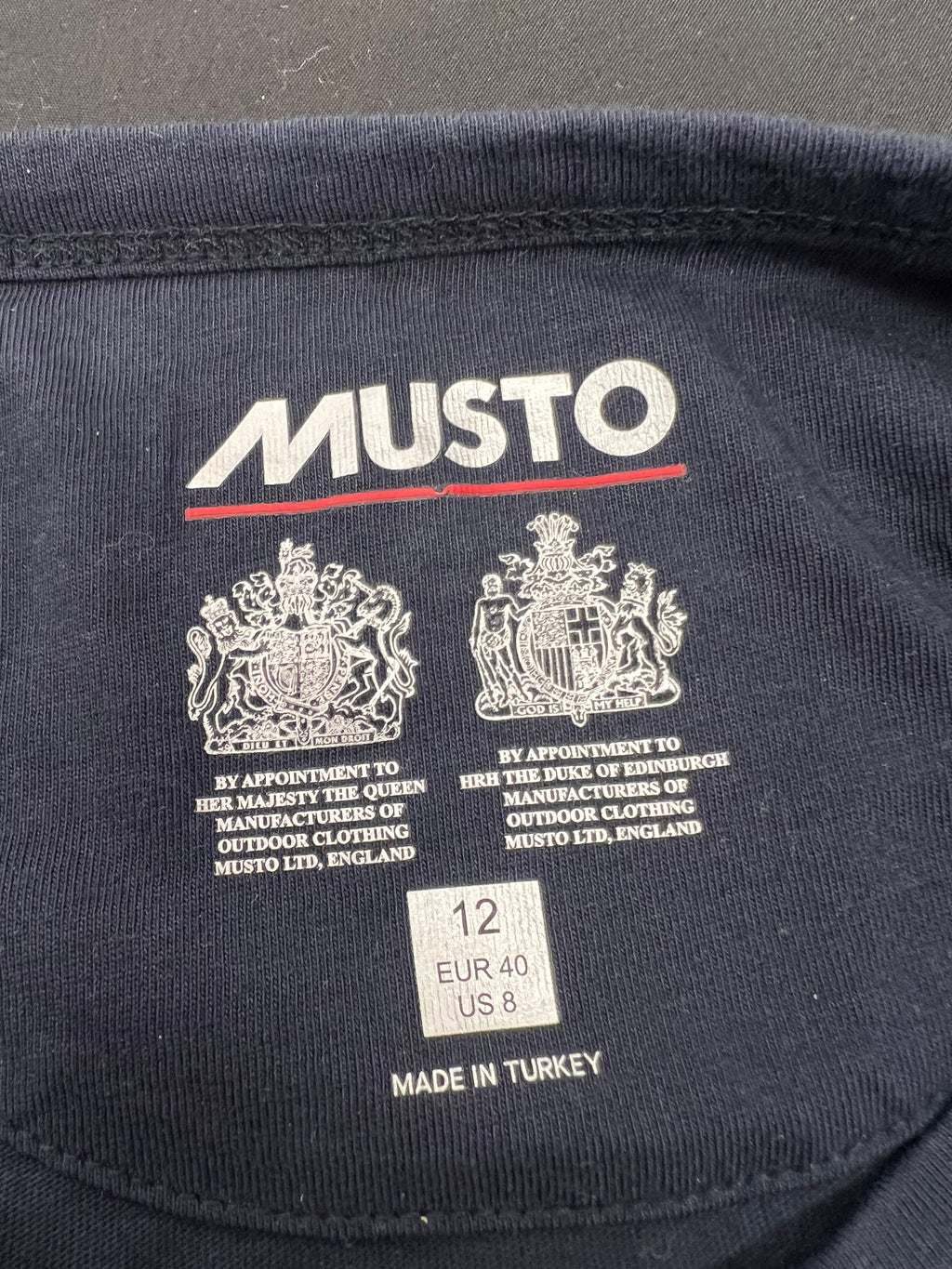 Interior neck label of Musto t-shirt showing royal appointments and size label 12, made in Turkey