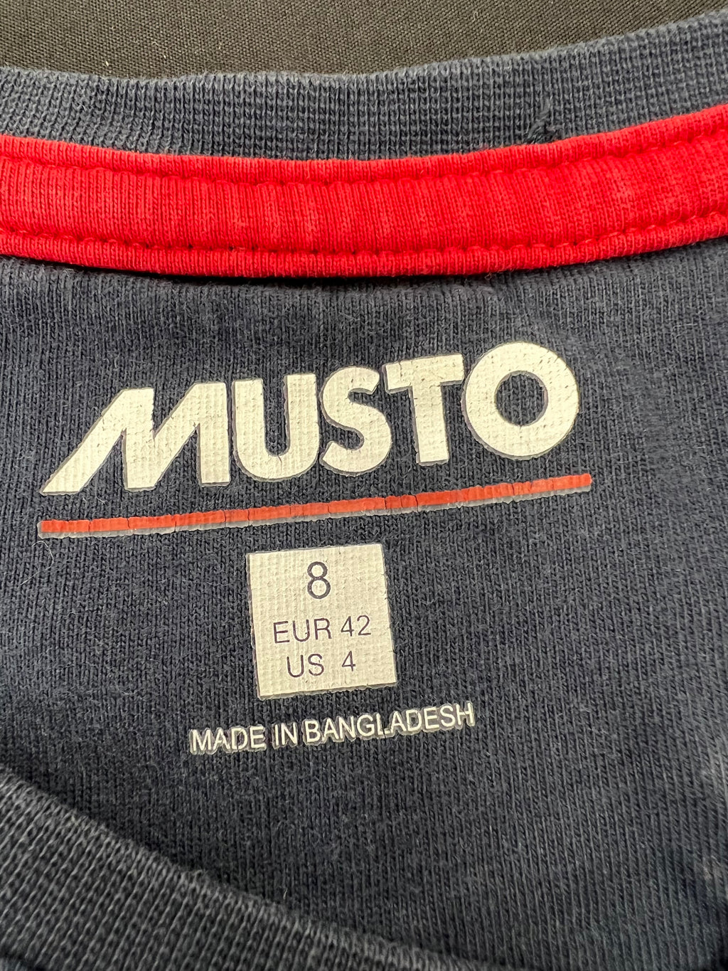 Interior neckline label of Musto size 8 navy T-shirt made in Bangladesh