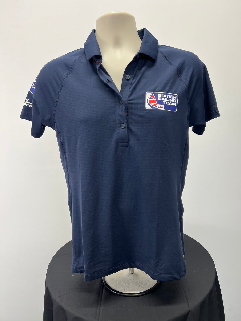 Front view of navy blue British Sailing Team women's polo shirt by Musto with button placket and logo on chest