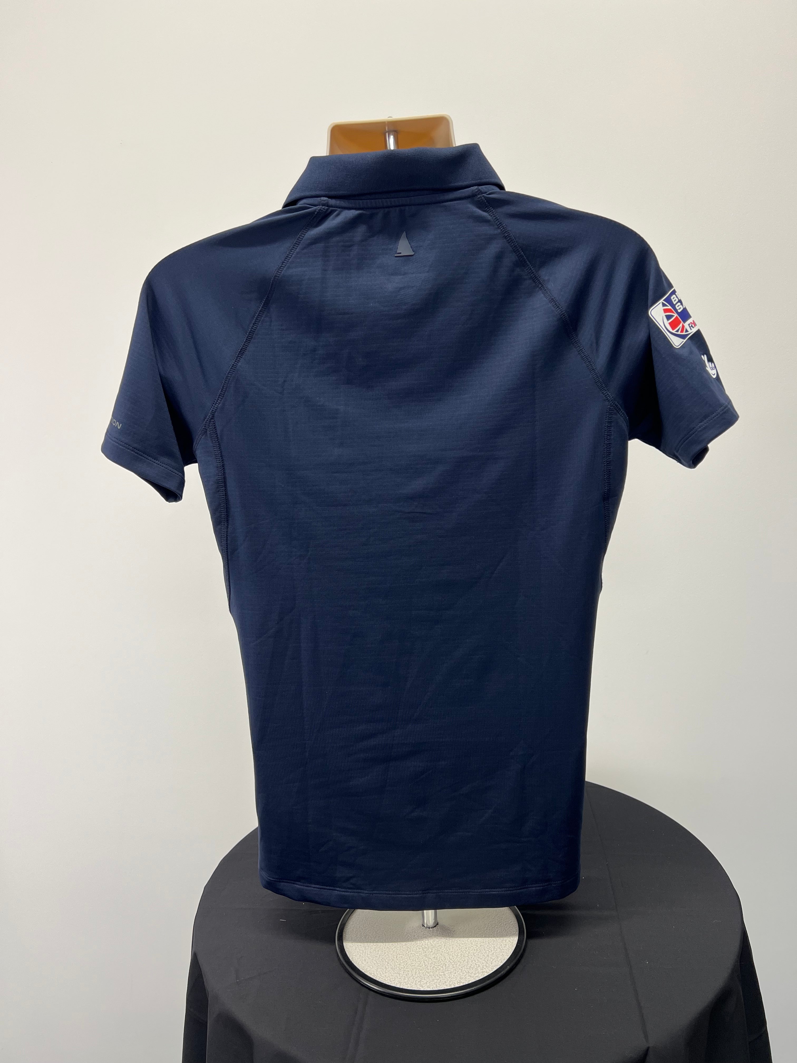 Back view of navy blue British Sailing Team women's polo shirt showing plain design and collar