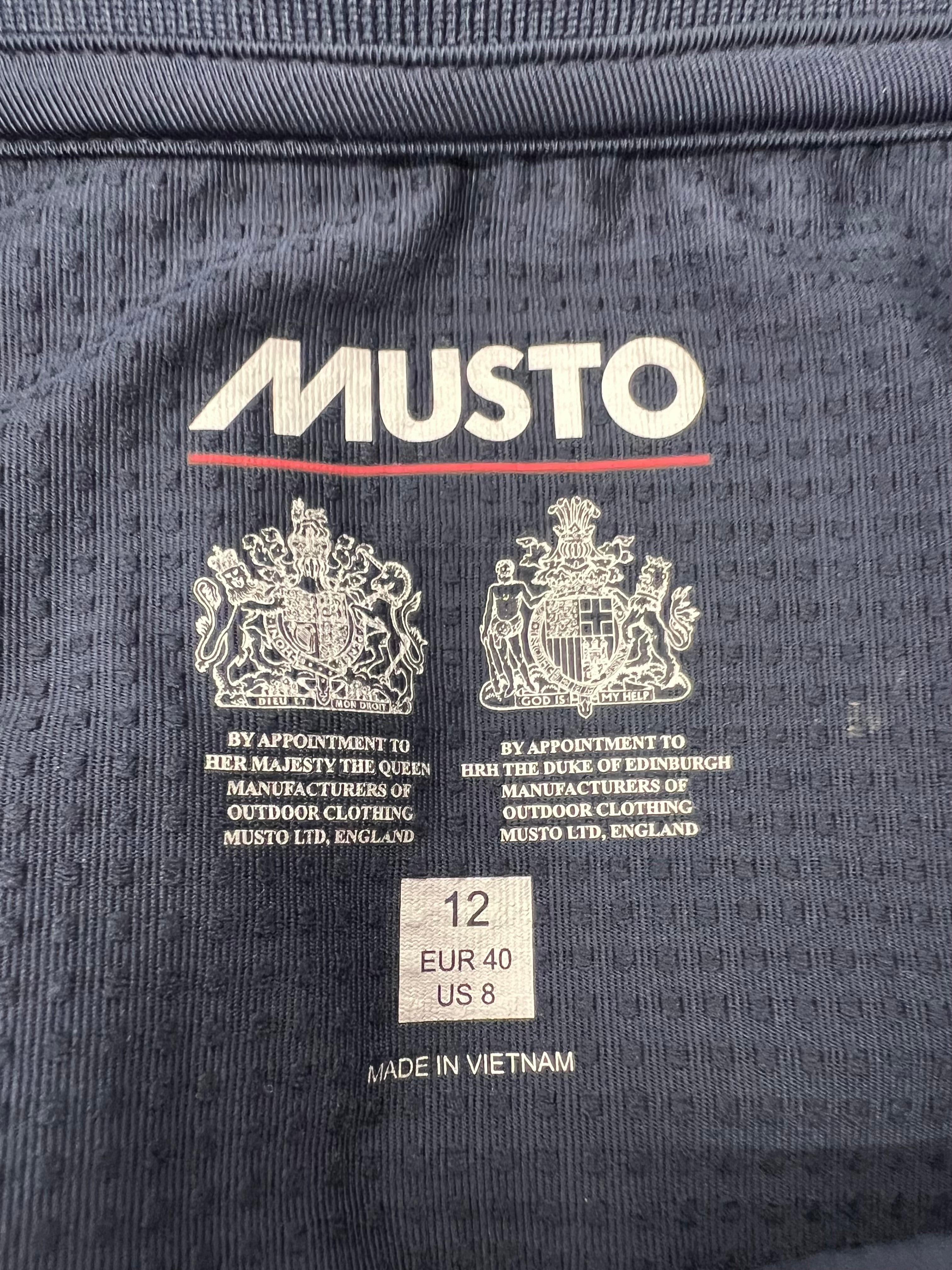 Close-up of Musto brand logo with Royal Warrants and size label inside shirt