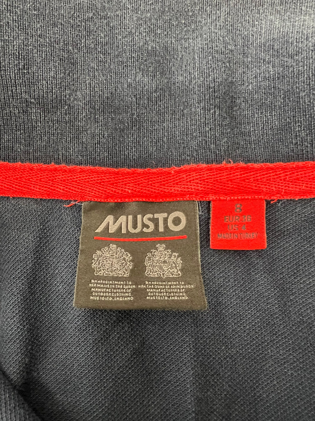 Label inside navy polo shirt reading Musto with size 8 and garment origins