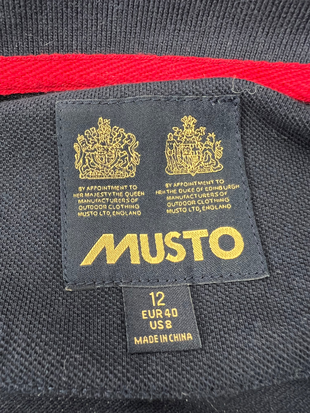 Close-up of Musto label inside navy polo shirt showing size 12 EUR 40 US 8 and care marks