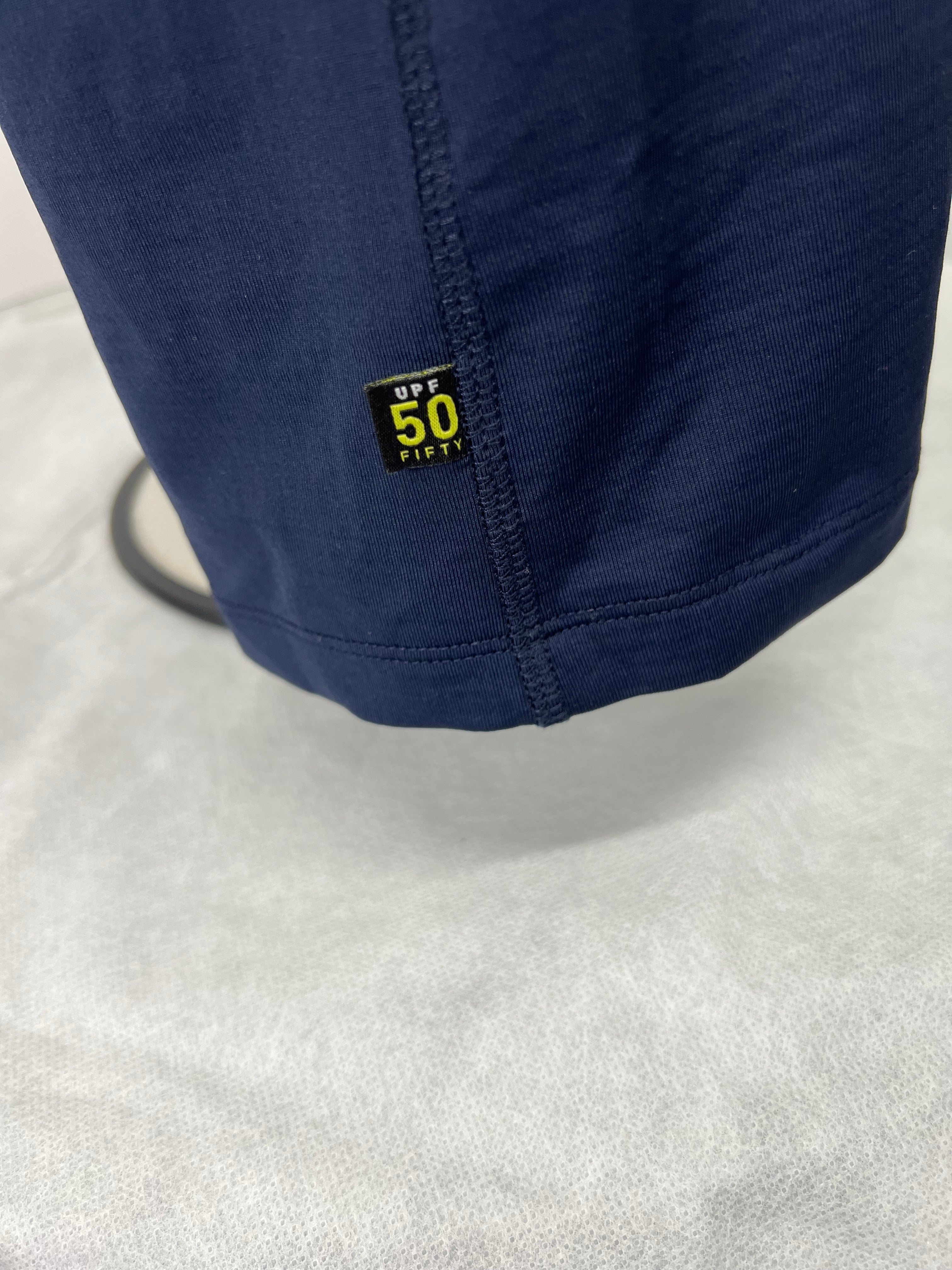 Close-up of UPF 50 tag stitched on navy polo shirt hem