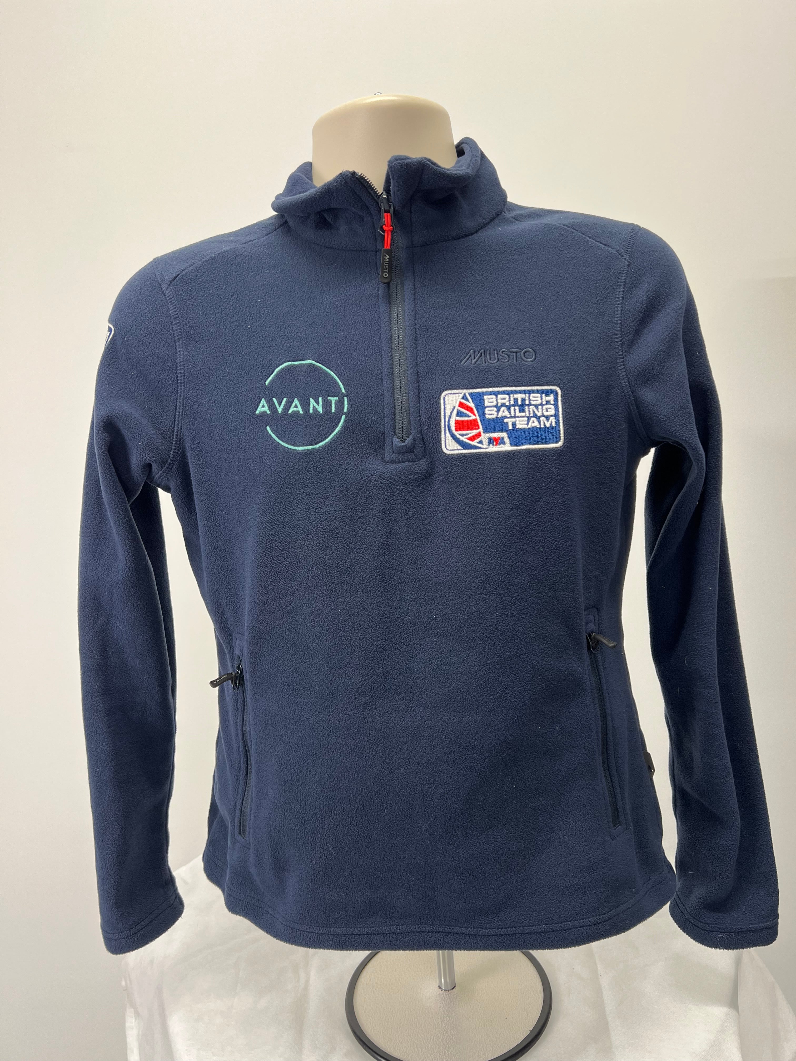 Front view of navy Musto fleece featuring British Sailing Team and Avanti logos with half zip and zippered pockets