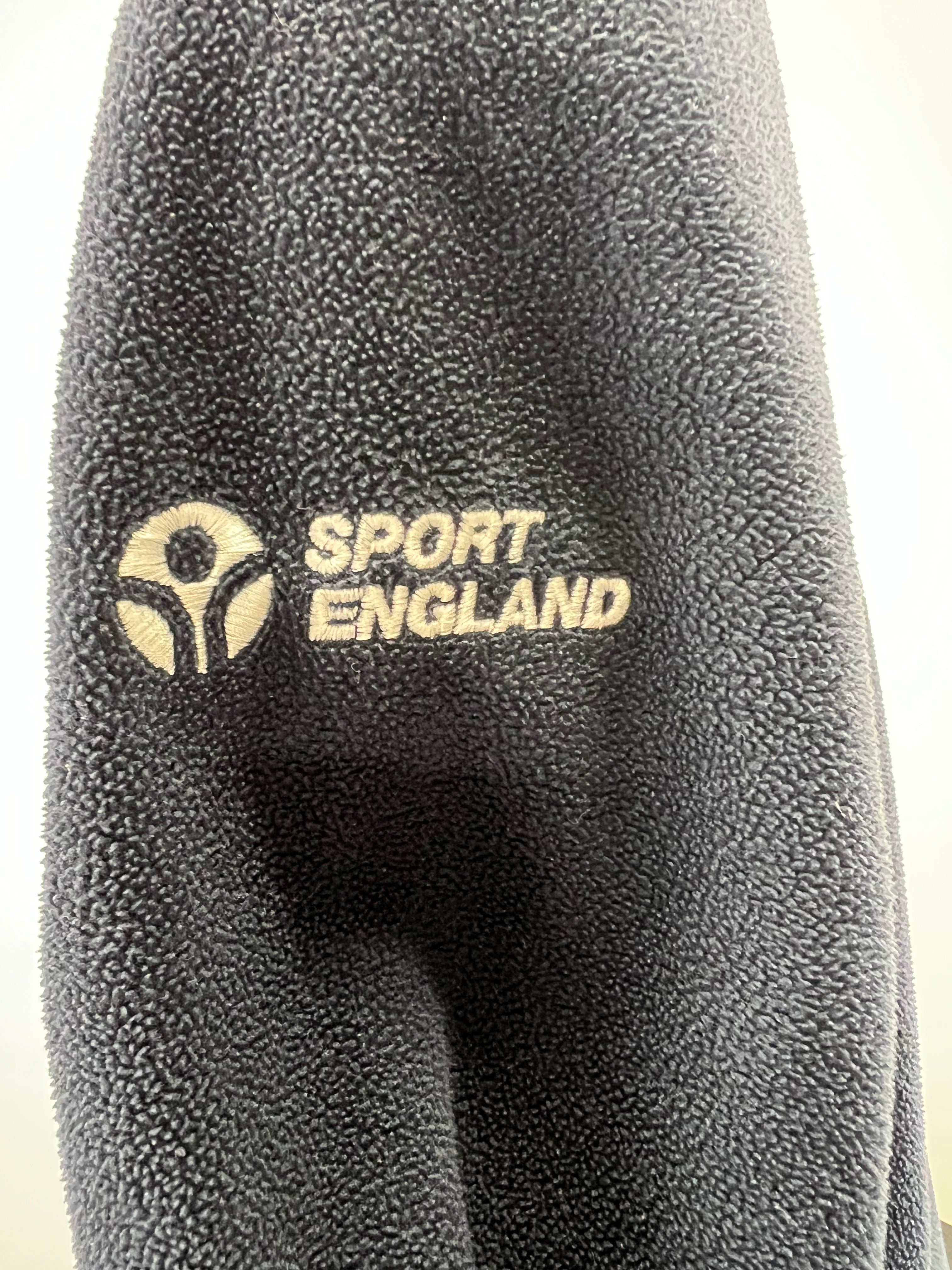 Close-up of black fleece fabric with embroidered Sport England logo on the sleeve