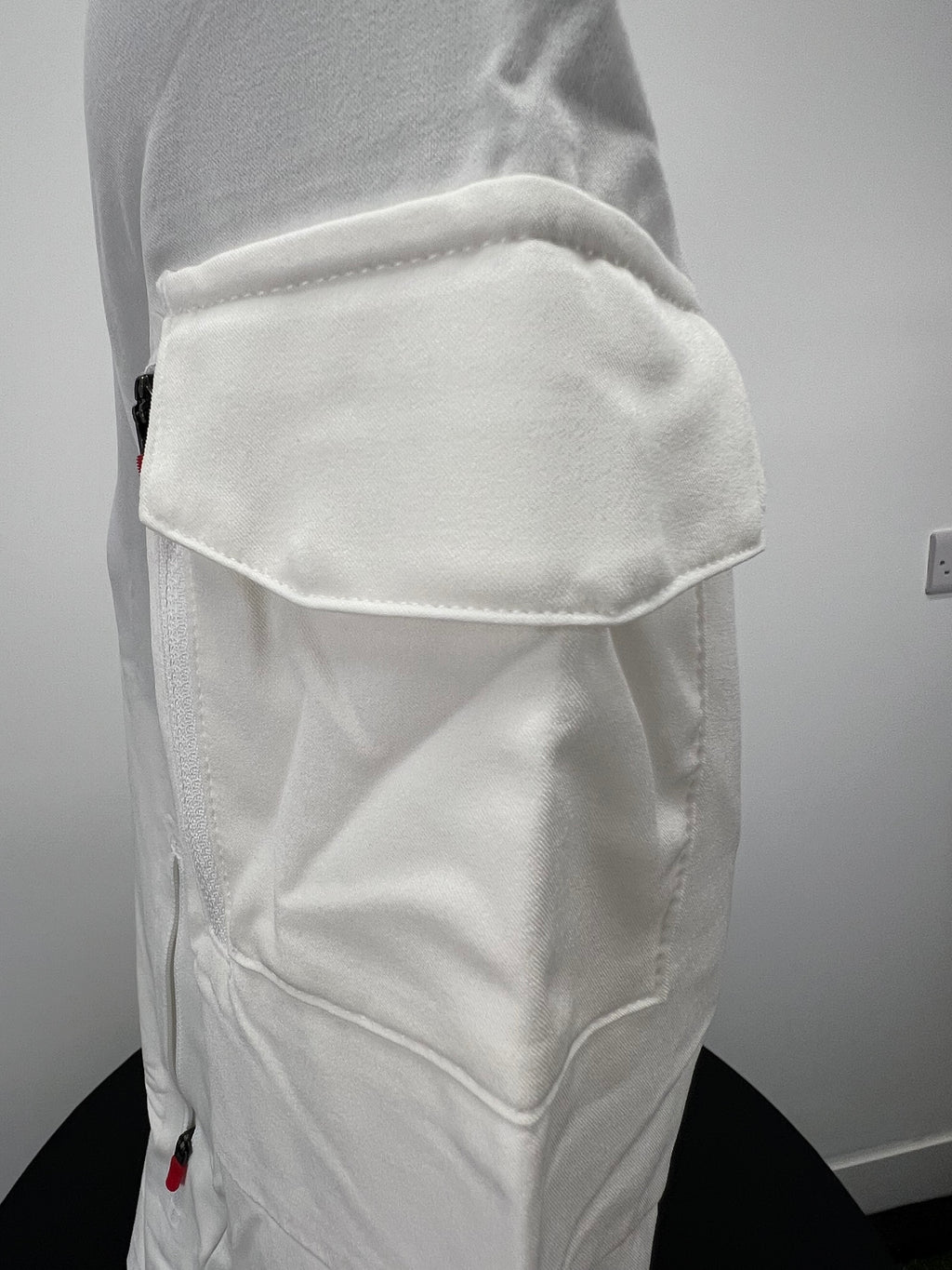 Close-up of zippered flap pocket on sleeve of cream Nike zip-up jacket