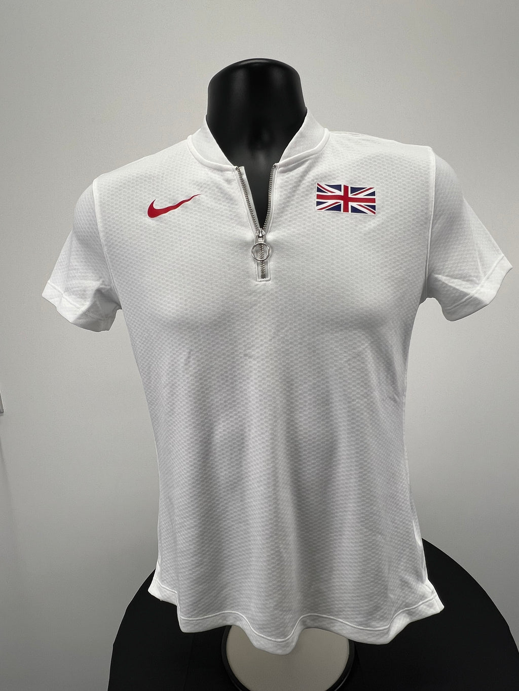 Front view of white Nike women’s half zip top with Union Jack and red swoosh logo