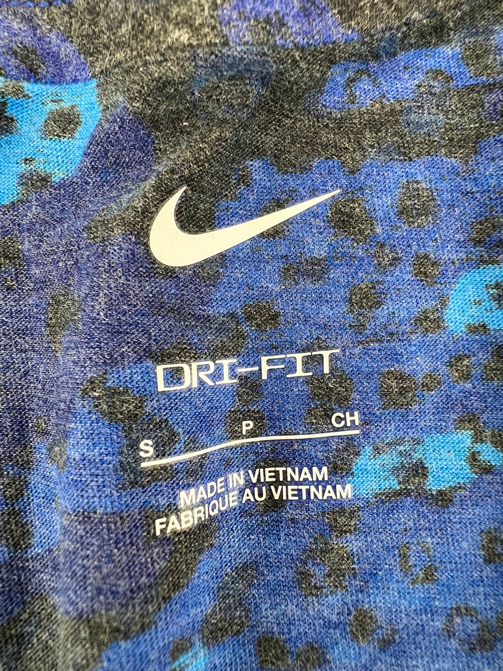 Close-up of Nike Dri-FIT logo and size label inside blue camouflage t-shirt