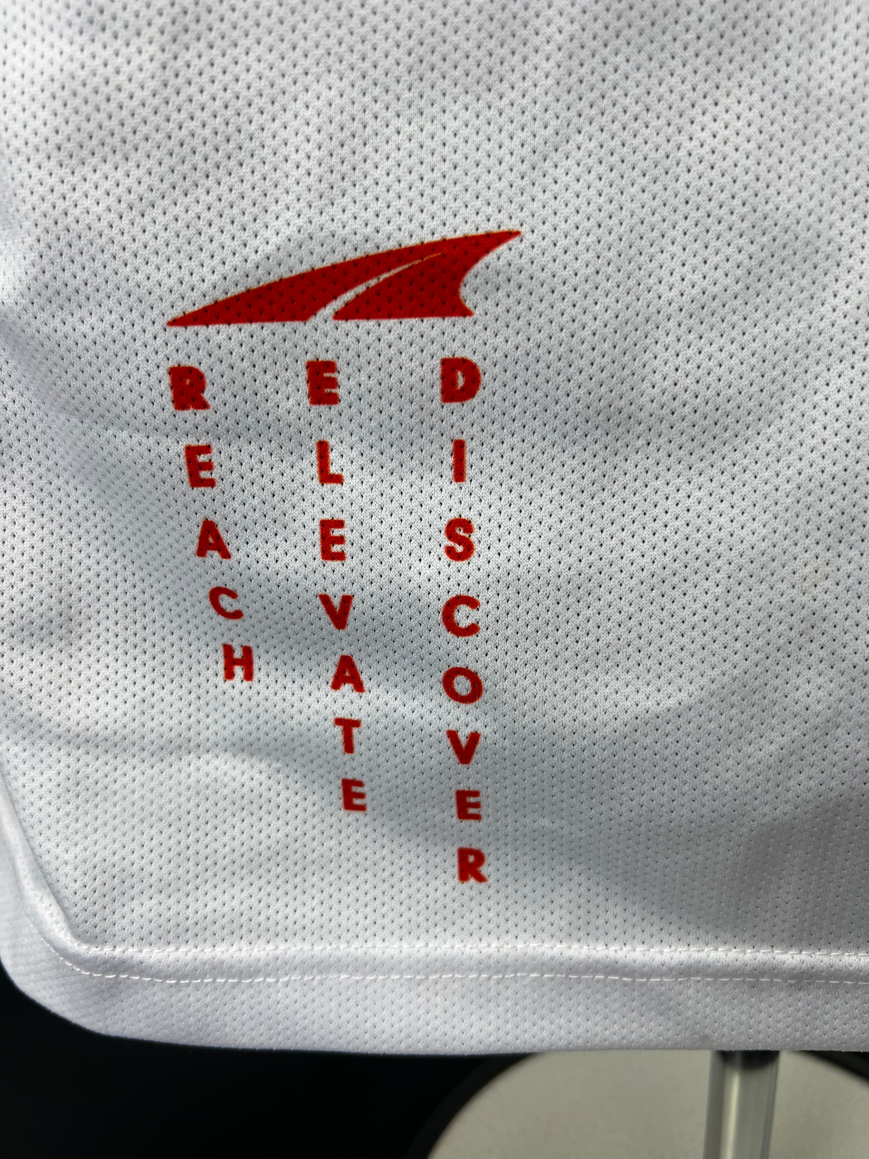 Close-up of motivational words 'Reach Elevate Discover' and Altra logo printed on lower front white section