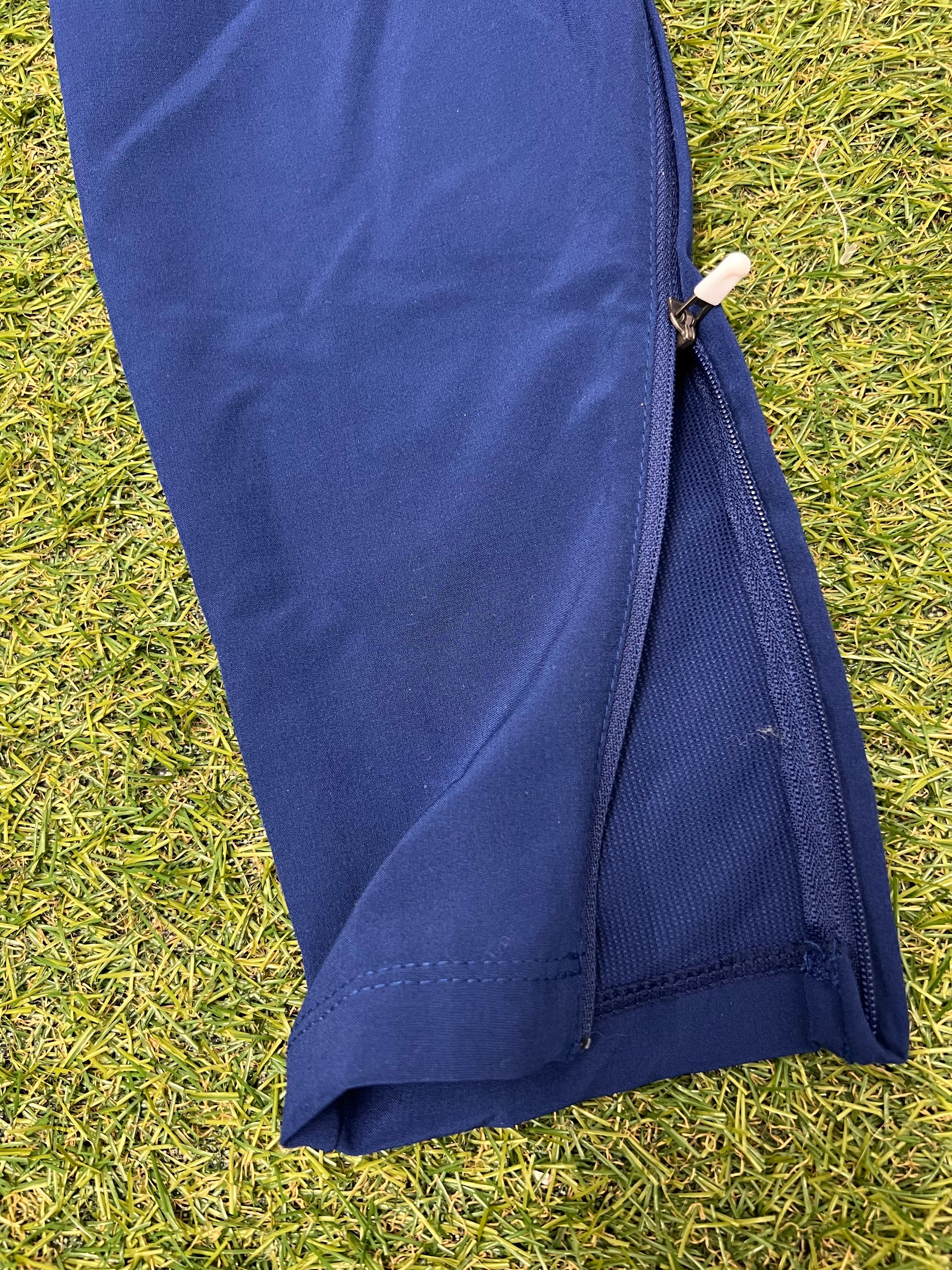 Close-up of zippered lower leg on navy blue Nike Women's Dri-FIT track pants highlighting fabric texture and zipper details
