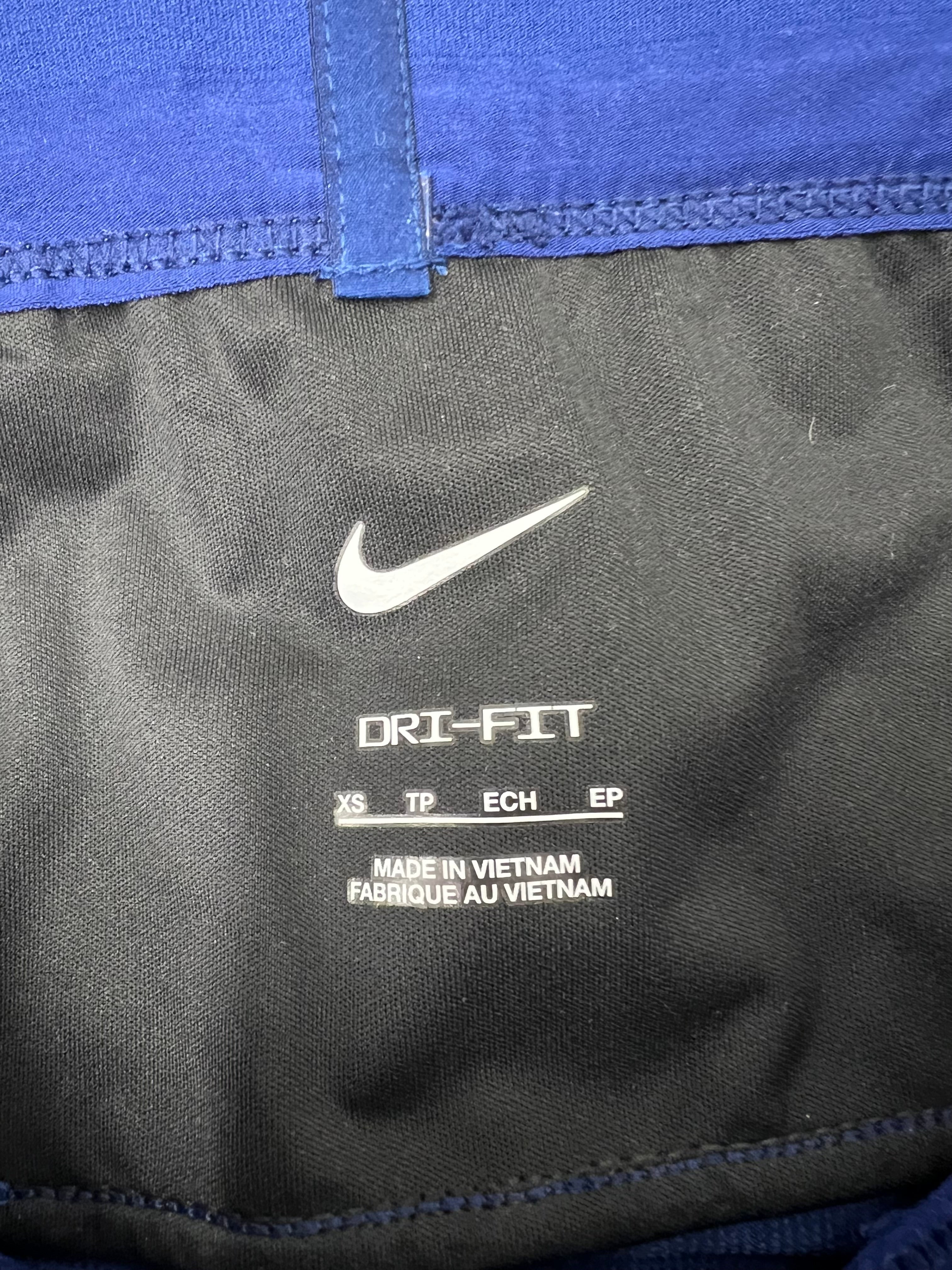 Nike Dri-FIT label and sizing tag inside blue women's athletic track pants